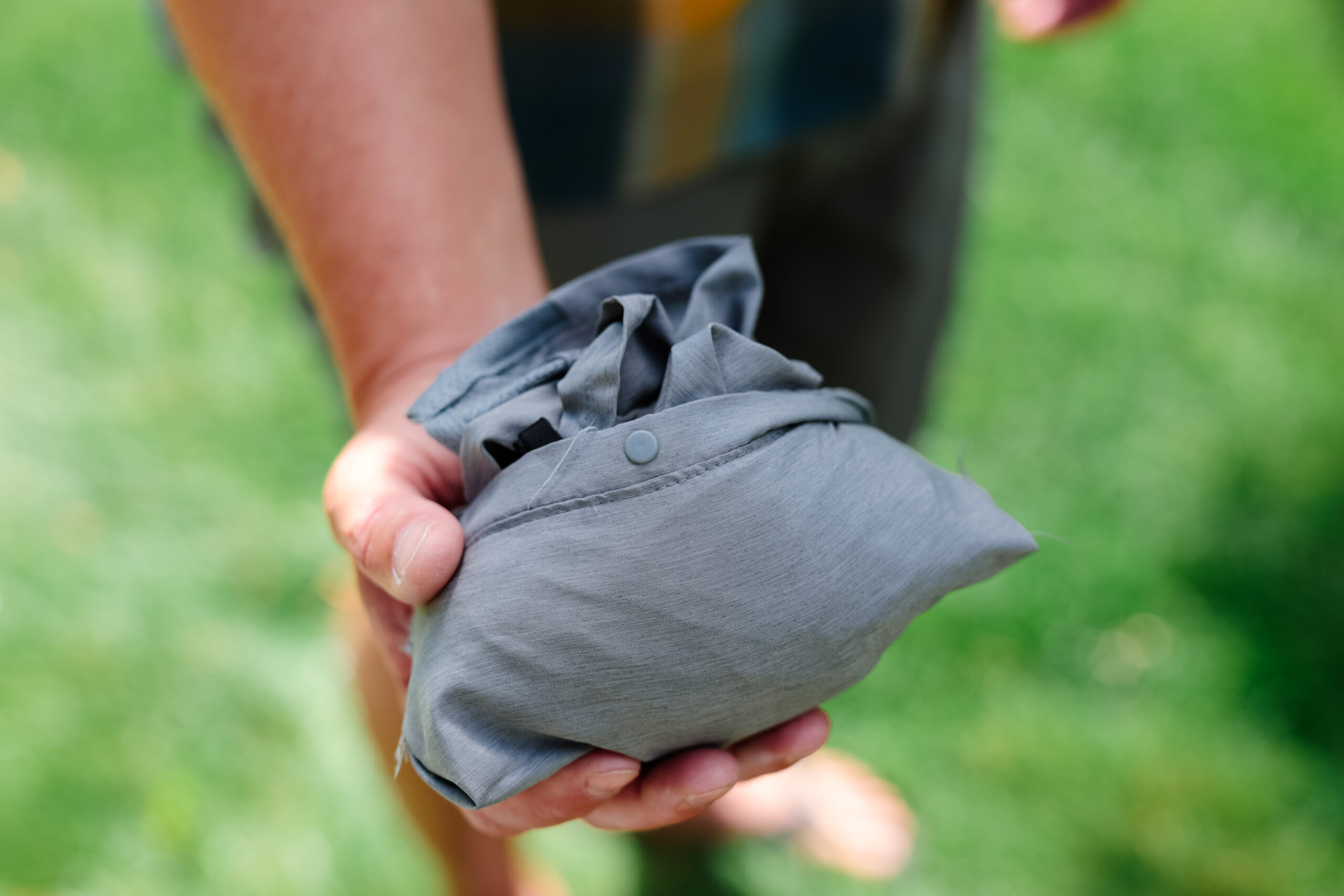 A pair of hiking shorts balled up into a pocket in a man's hand.