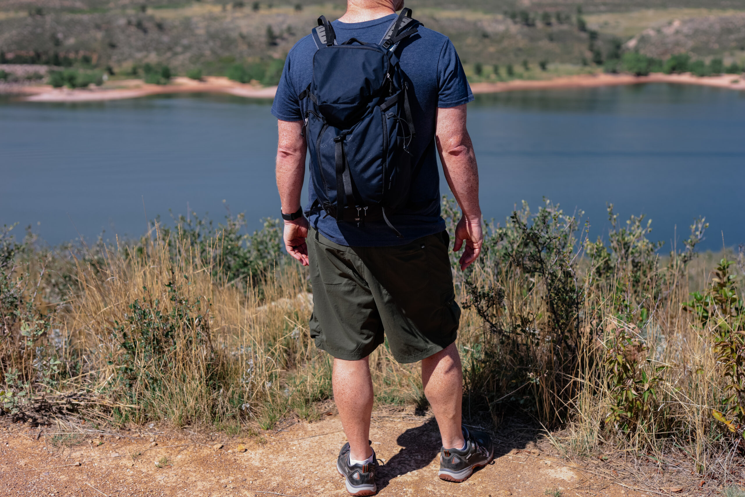 Man standing by lake in shorts.