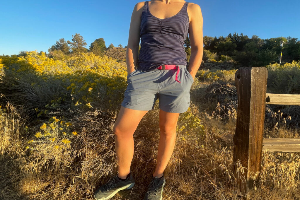 a hiker posing next to a fence in a field of rabbit brush and sage in the sunny high desert