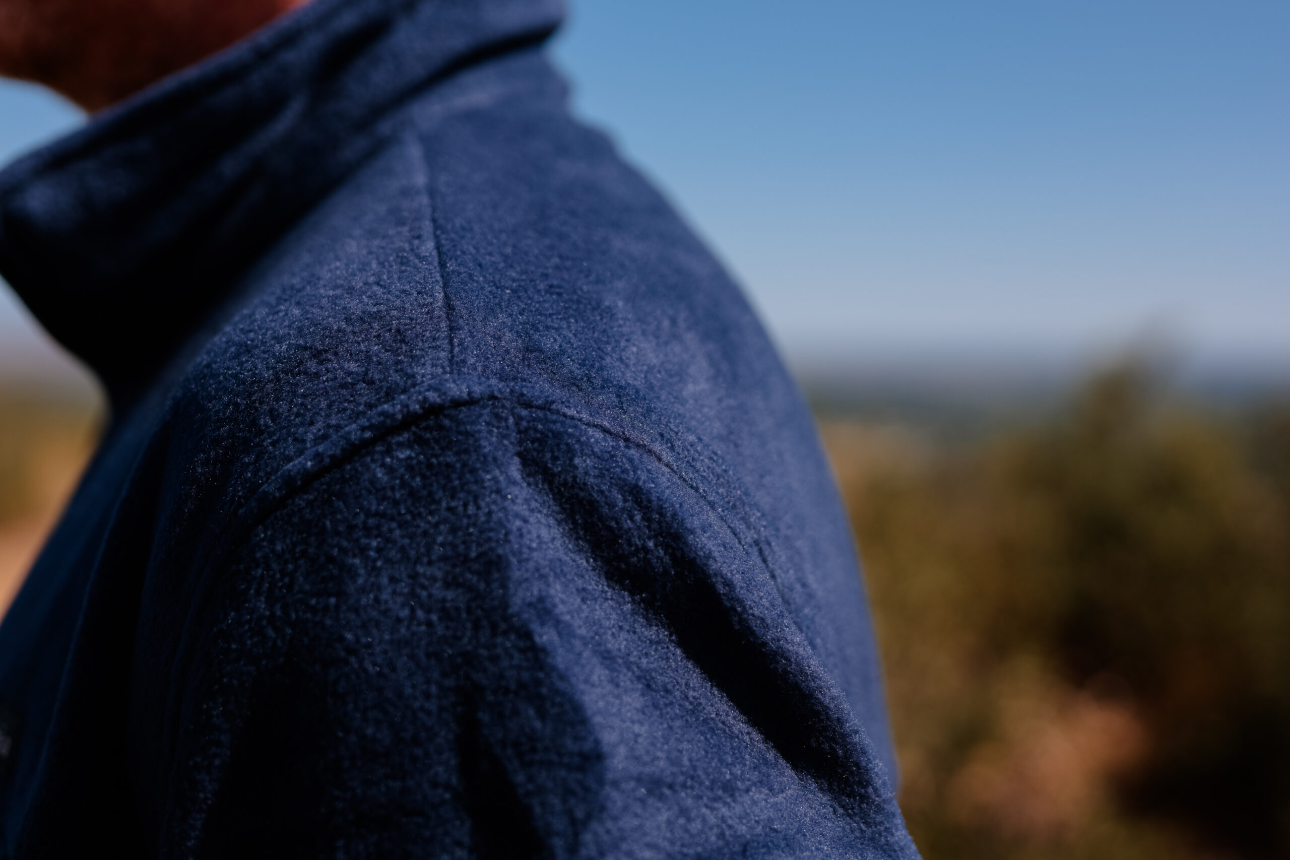 The shoulder of a blue fleece close up.