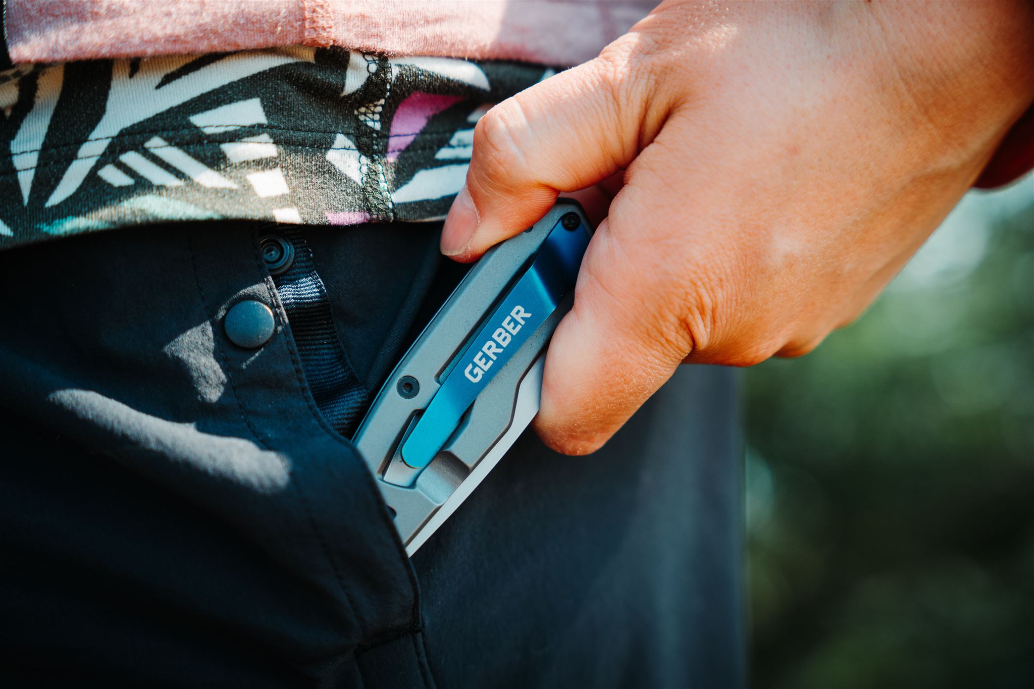 Close up of the Gerber Paralite pocket knife being put in the pocket of black shorts