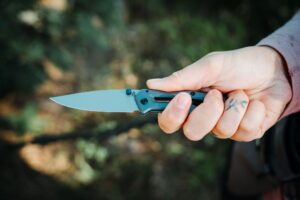 Holding the Gerber Paralite pocket knife with an outdoor background