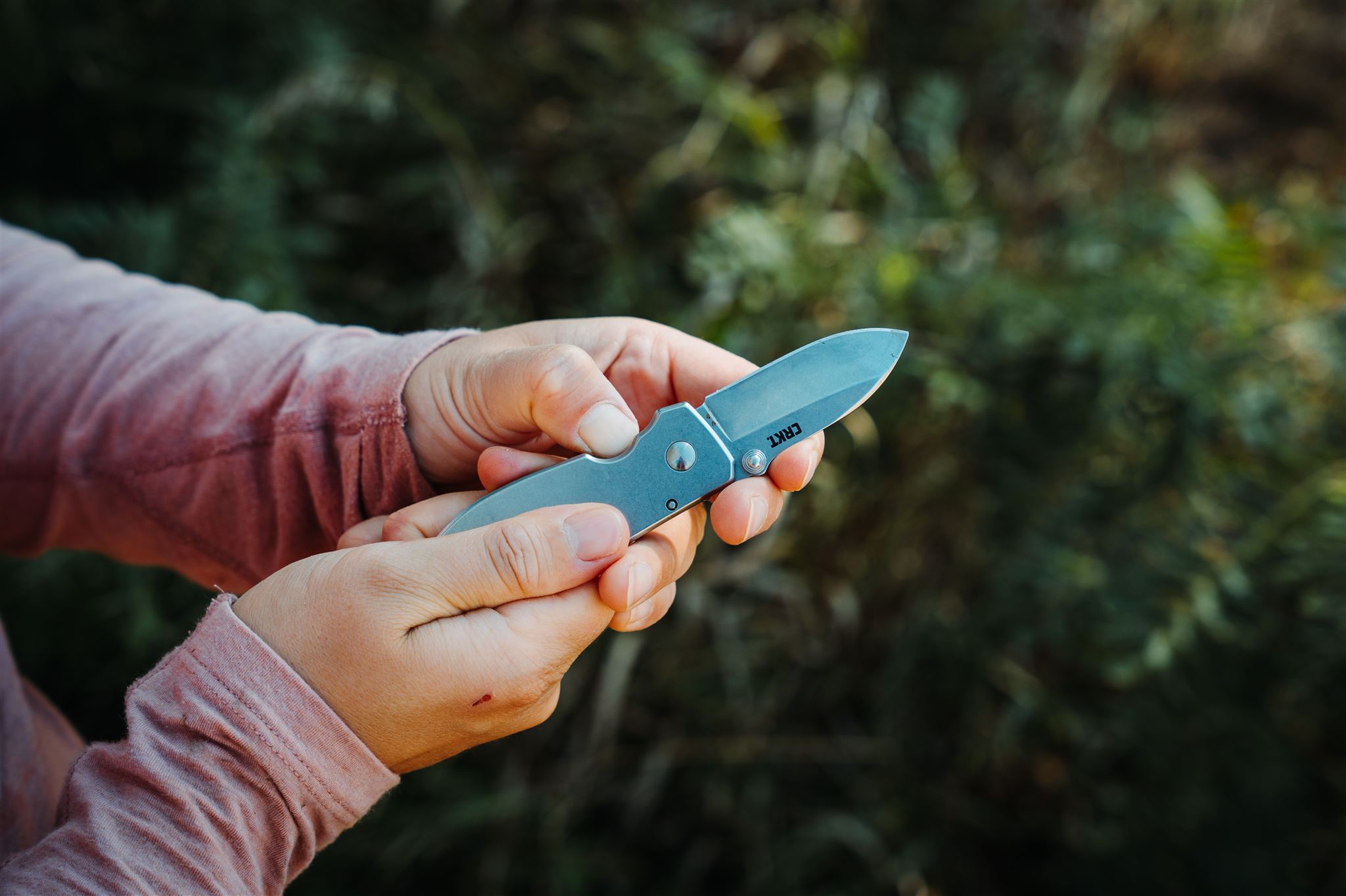 Demonstrating the use of the frame lock on the CRKT Squid pocket knife with an outdoor background