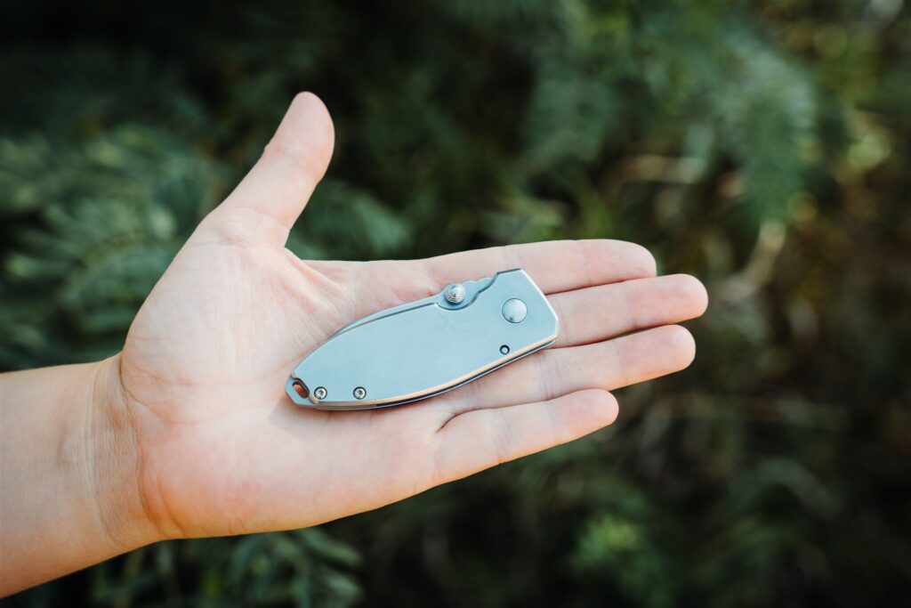 Holding the closed CRKT Squid pocket knife in palm of hand with outdoor background