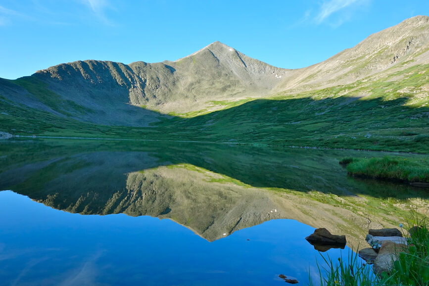 high alpine lake with the mountains and blue sky reflected on the still lake.