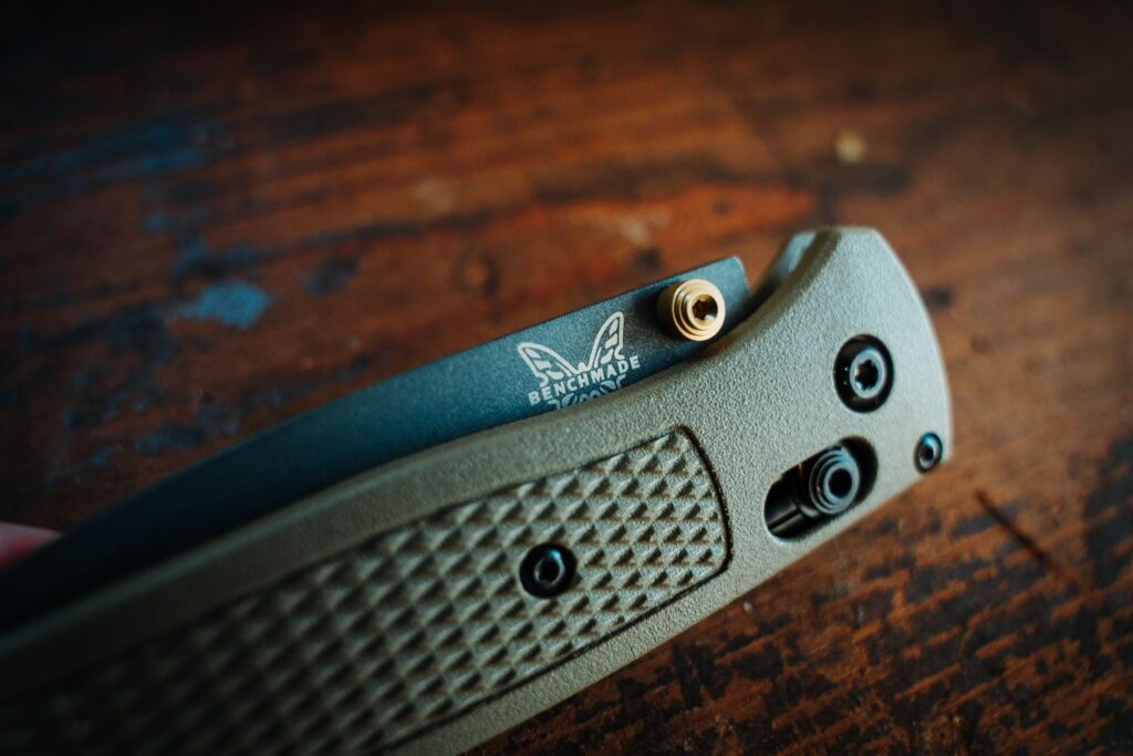 A close up of the Benchmade Bugout 535 pocket knife closed with a wooden background to show the AXIS locking mechanism