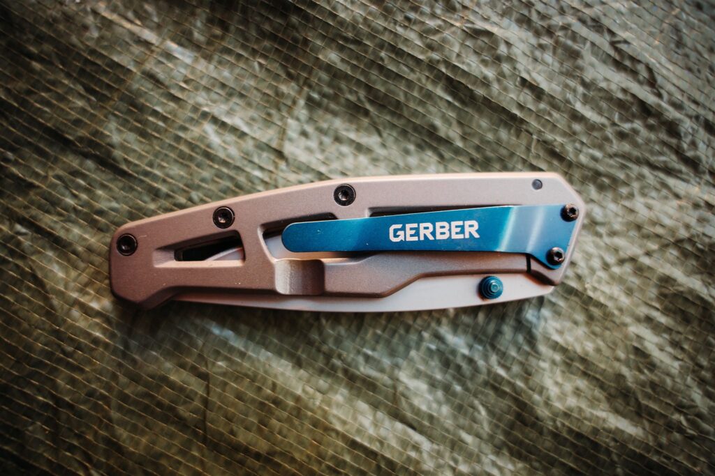 Product photo of the Gerber Paralite pocket knife while closed showing the pocket clip on a green background