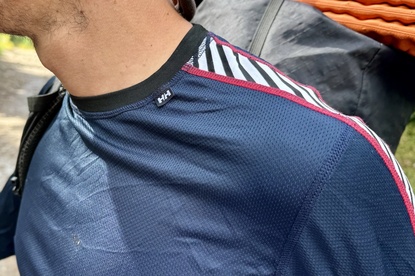 A close up of the crew neck on the Helly Hansen Lifa Stripe base layer. The base layer is being worn by a hiker and his pack can be seen in the background.