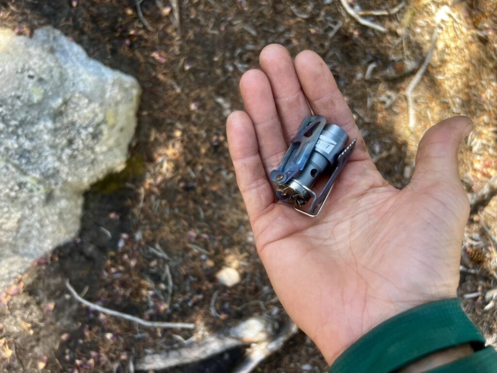 A photo of the BRS 3000T fitting easily into the palm of a hand. Dirt and rocks in the background.