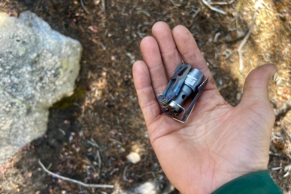 A photo of the BRS 3000T fitting easily into the palm of a hand. Dirt and rocks in the background.