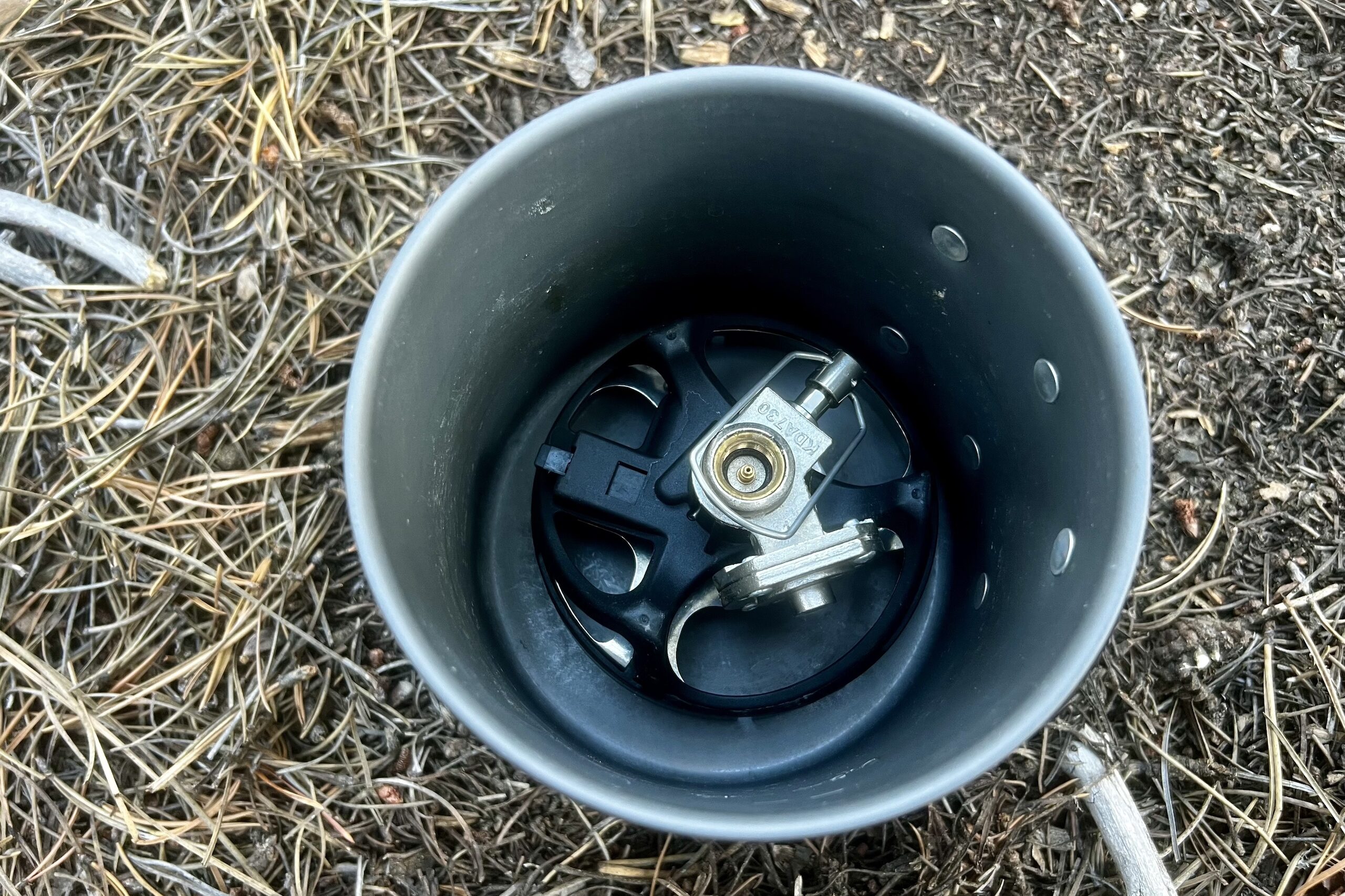 An above shot of the MiniMo burner inside its pot. Forest floor background.