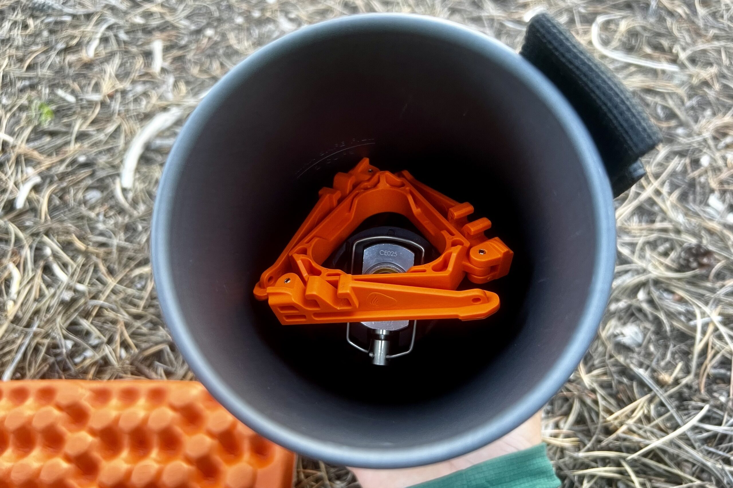 An arial shot of the burner and canister support of the JetBoil Flash packed into the included pot. Pine needle background.