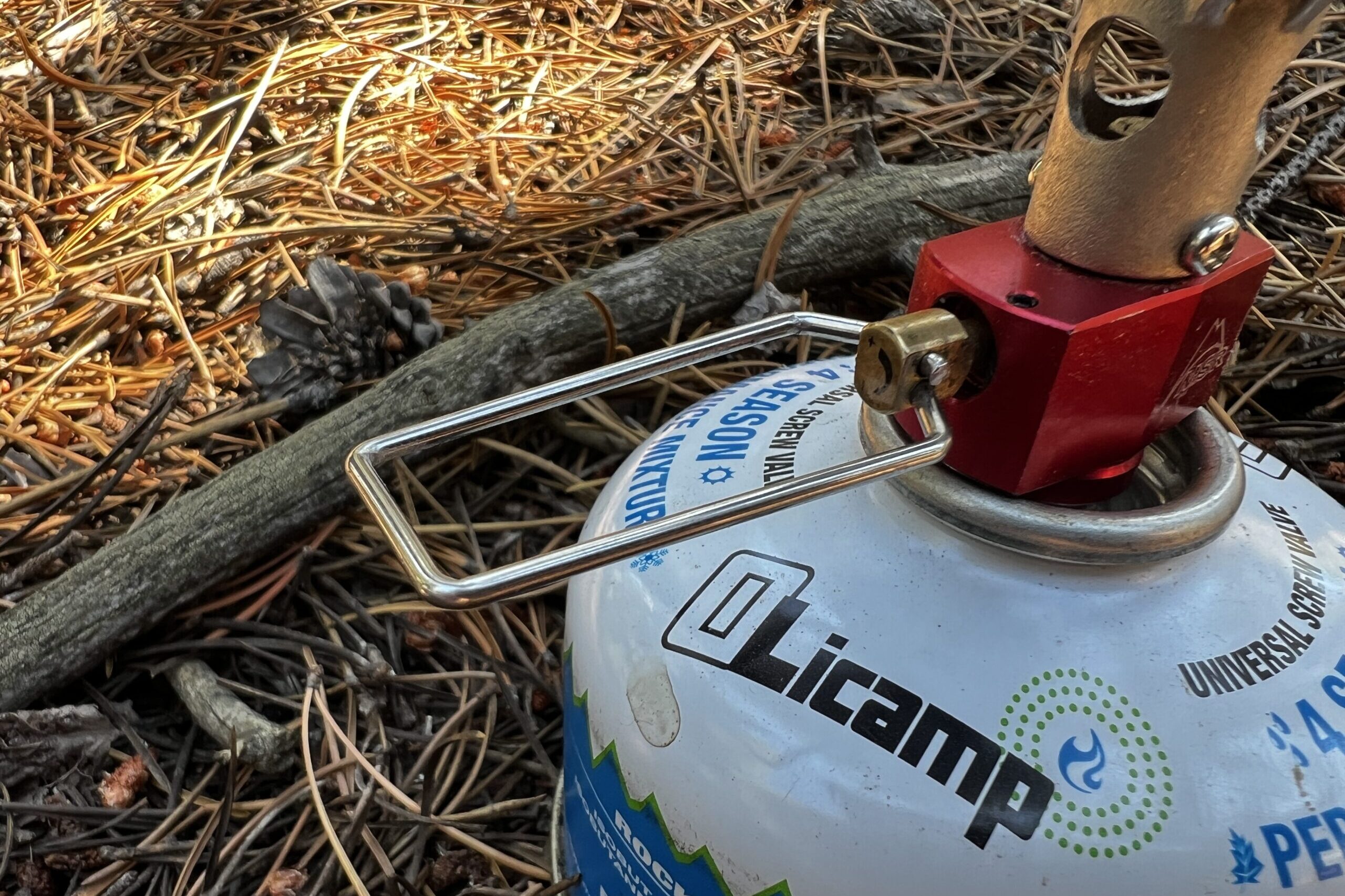 An up-close shot of the fuel control valve on the PocketRocket 2 with installed fuel canister. The stove sits on pine needles.