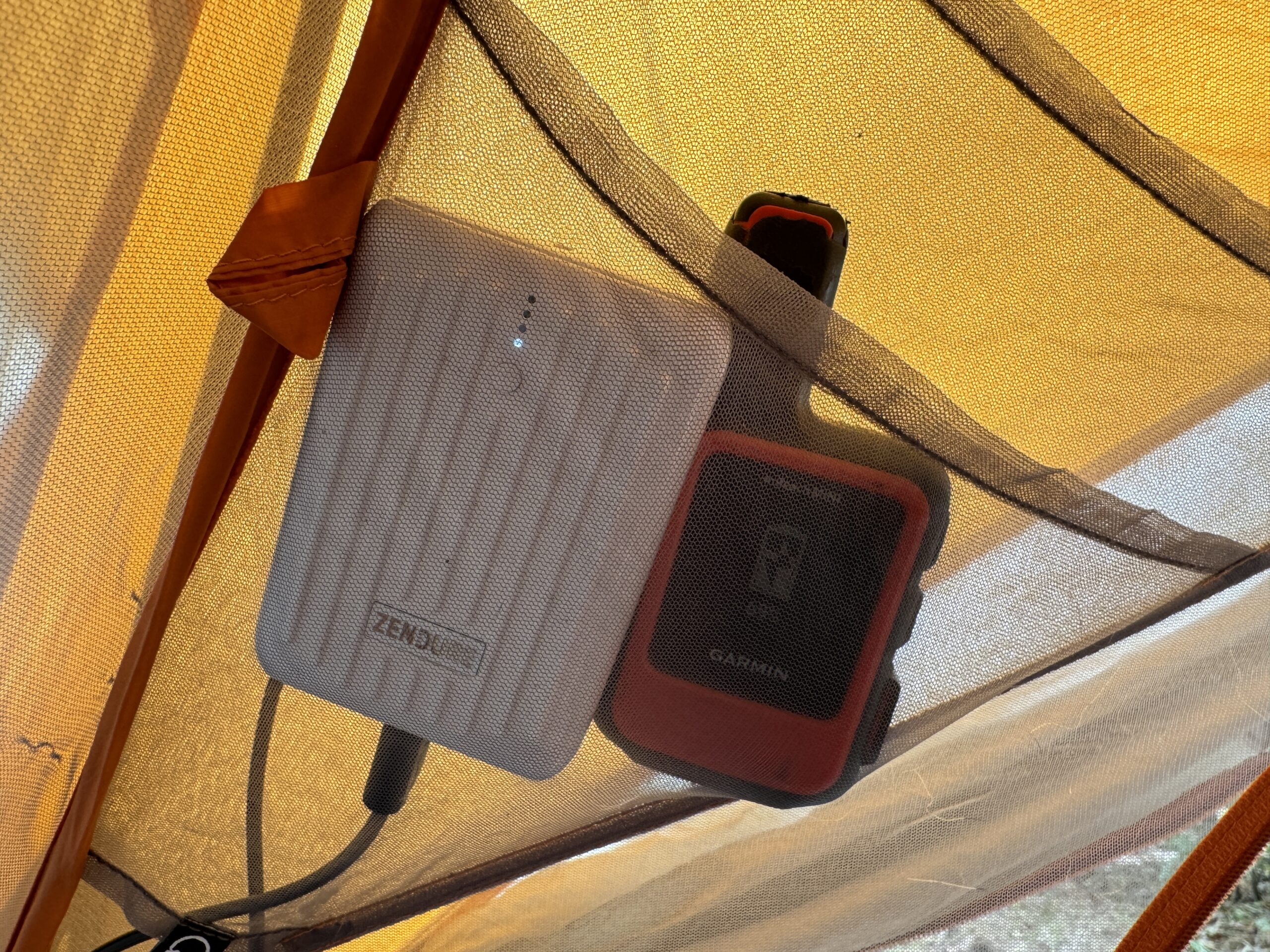 Close up of the Zendure Super Mini and a Garmin Inreach sitting in a tent pocket.