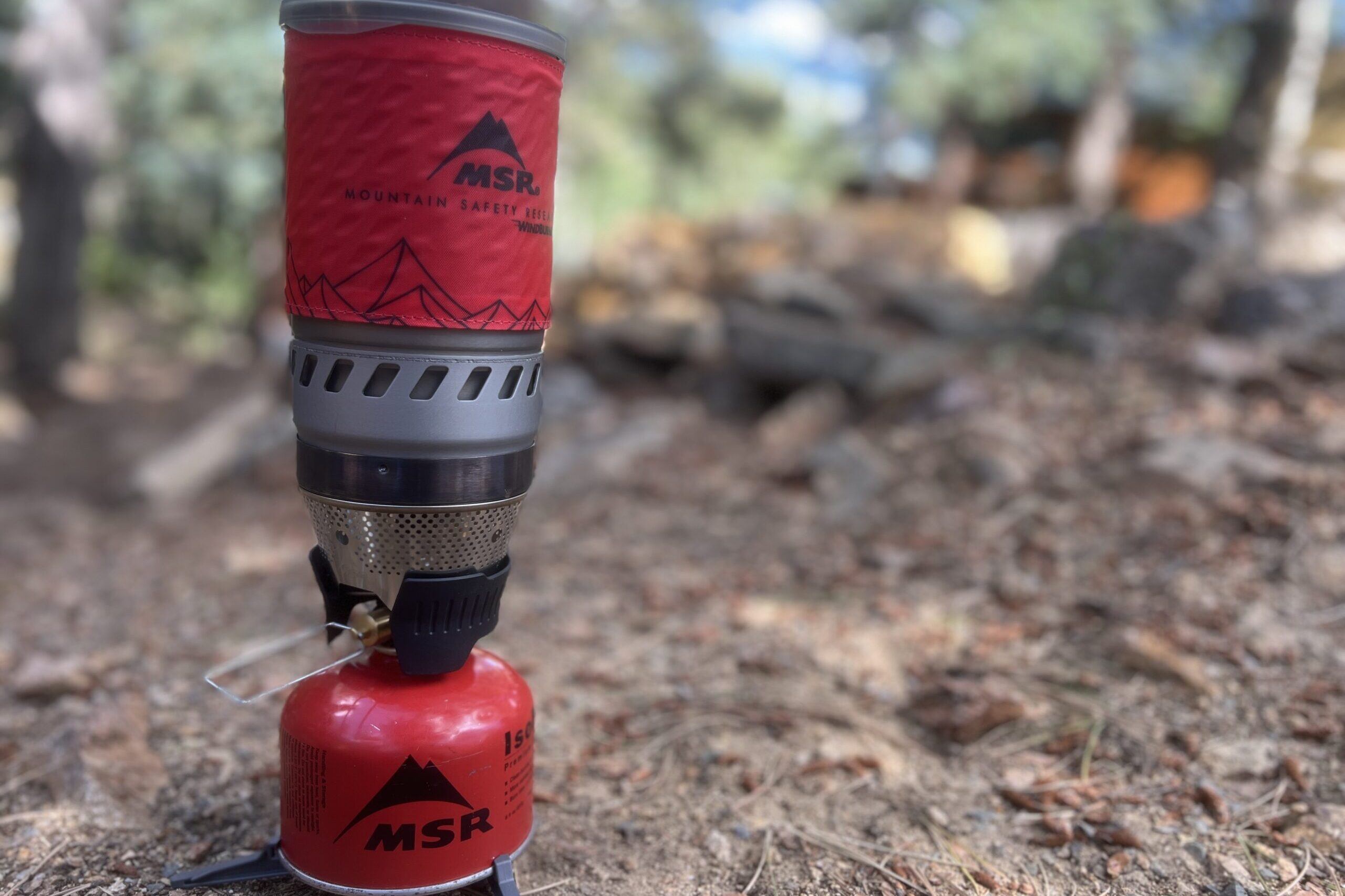 A side shot of the WindBurner completely installed with pot, stove, fuel, and canister stand. The background is blurry.