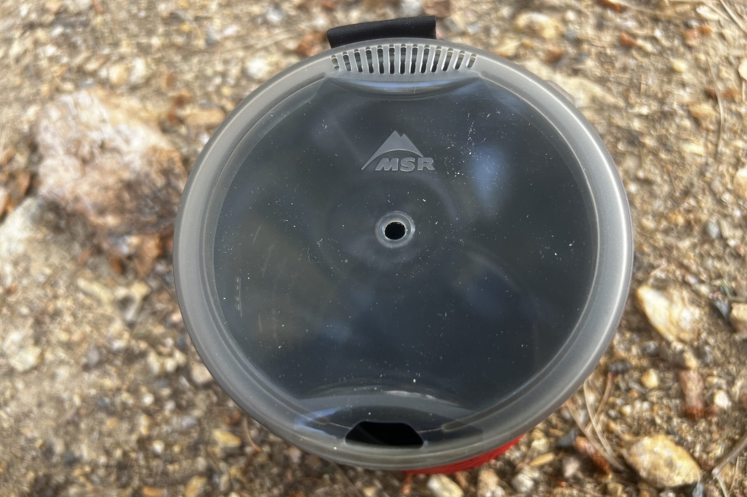 A top view of the lid of the MSR WindBurner on a gravel background.