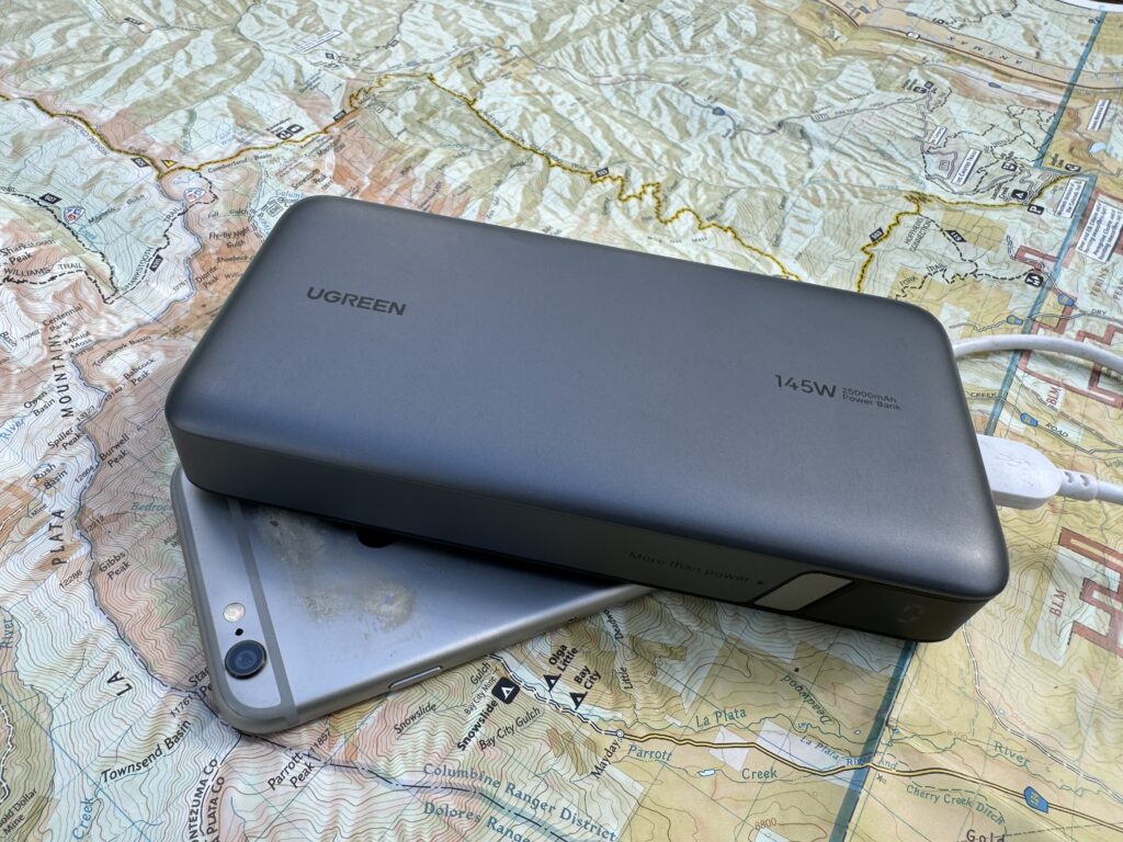 The UGREEN power bank and a phone sit on a map.