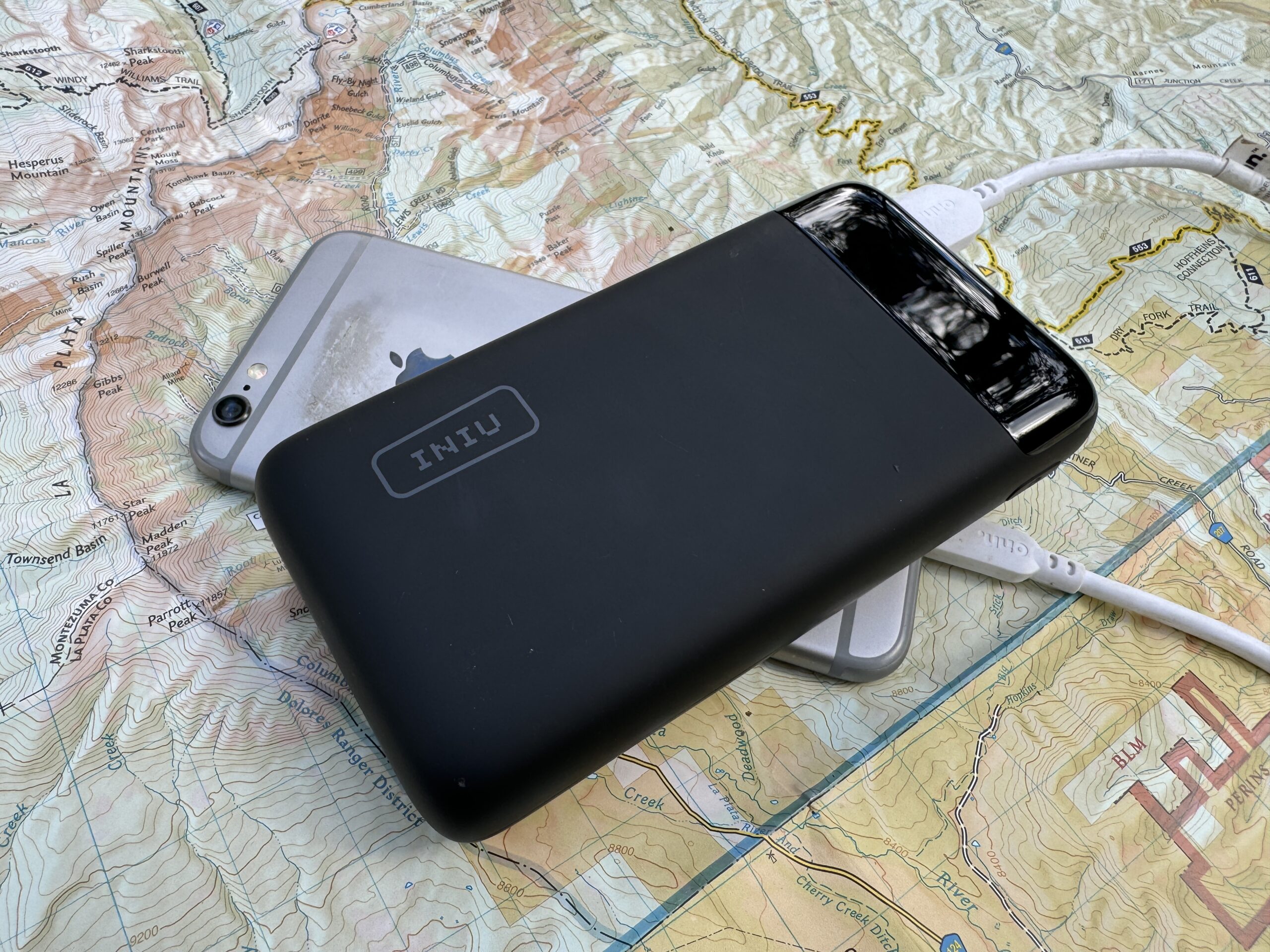 The INIU 20000 PD power bank and a phone sit on a map.