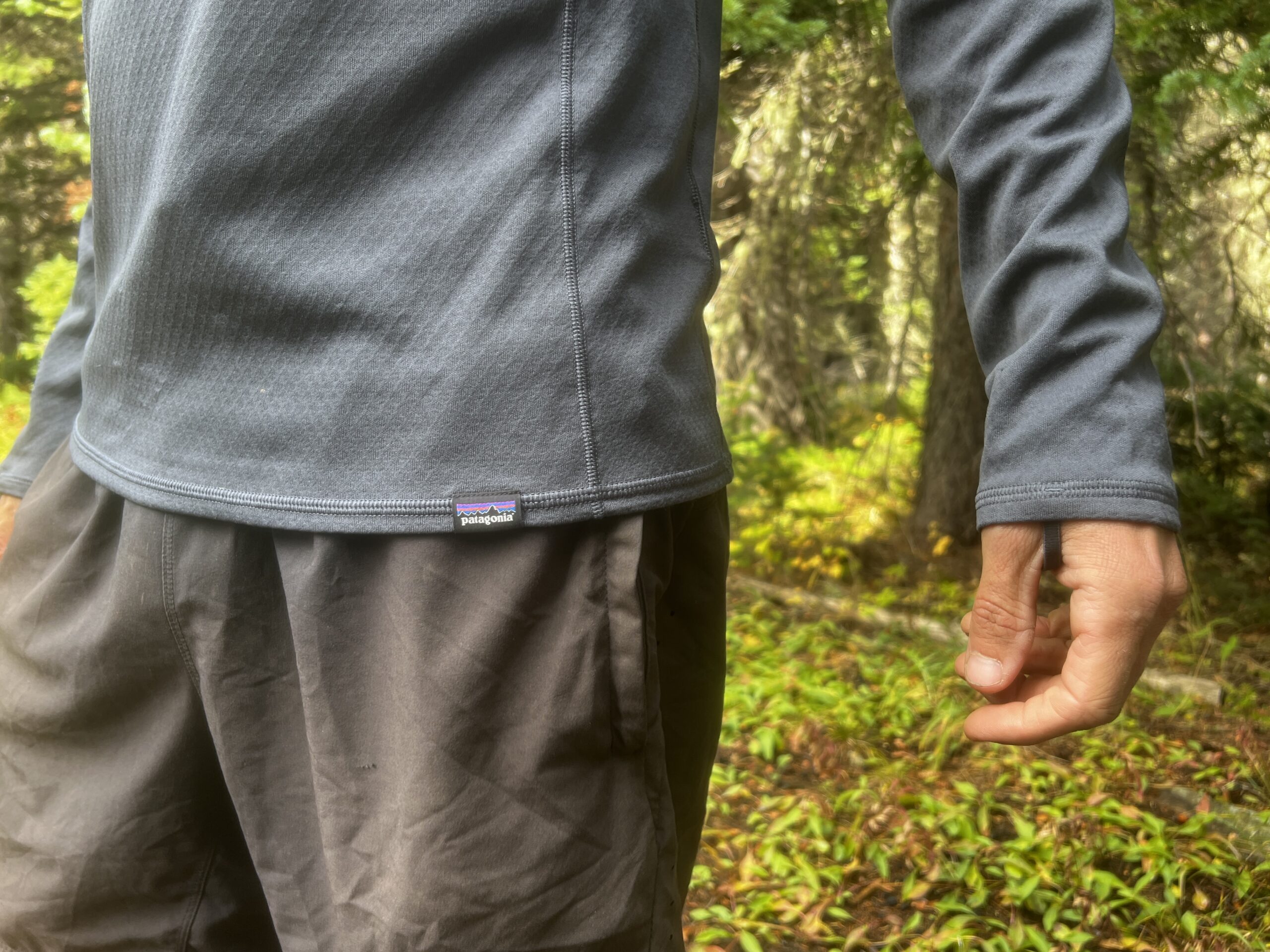 A close up of the wrists of the Patagonia Capilene base layer while being worn by a hiker. Trees are in the background.