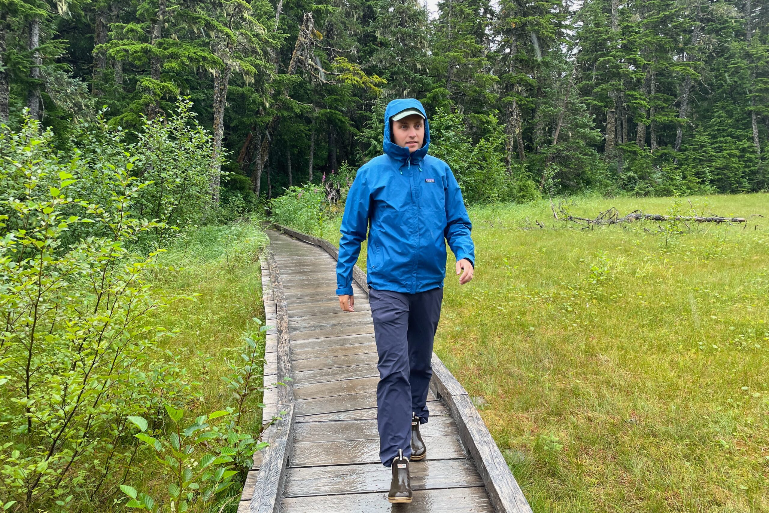 A man walks down a boardwalk on a rainy day.