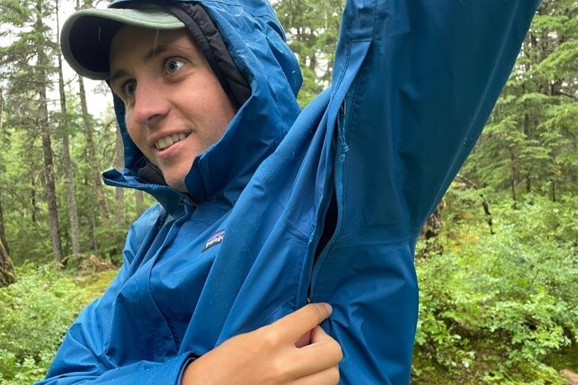 A man unzips the vents of his rain jacket.