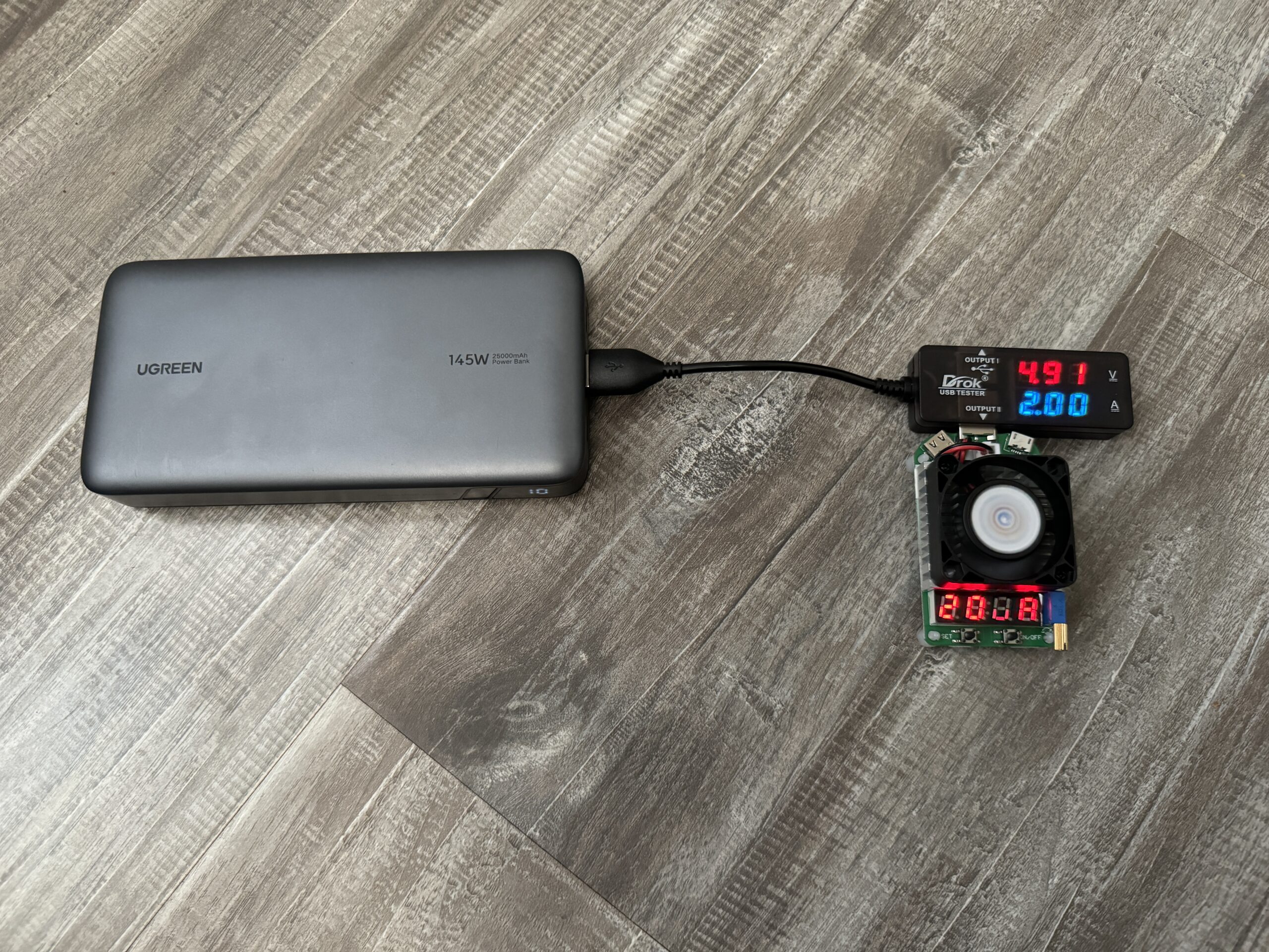 Close up of the UGREEN power bank plugged into a multimeter and dummy resistor load.