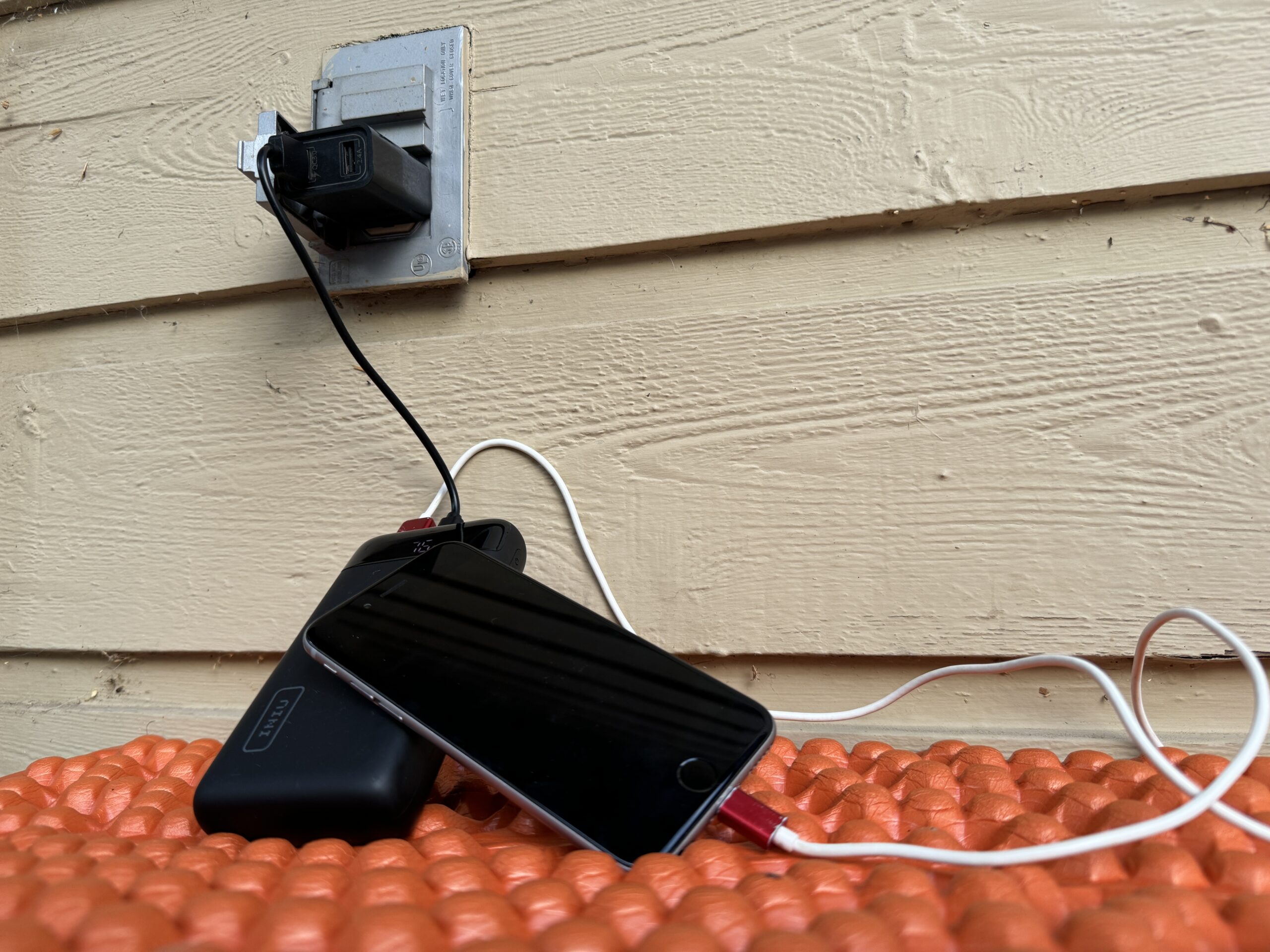 Close up of the INIU 20000 PD charging from an outlet and a cell phone charging from the power bank simultaneously.