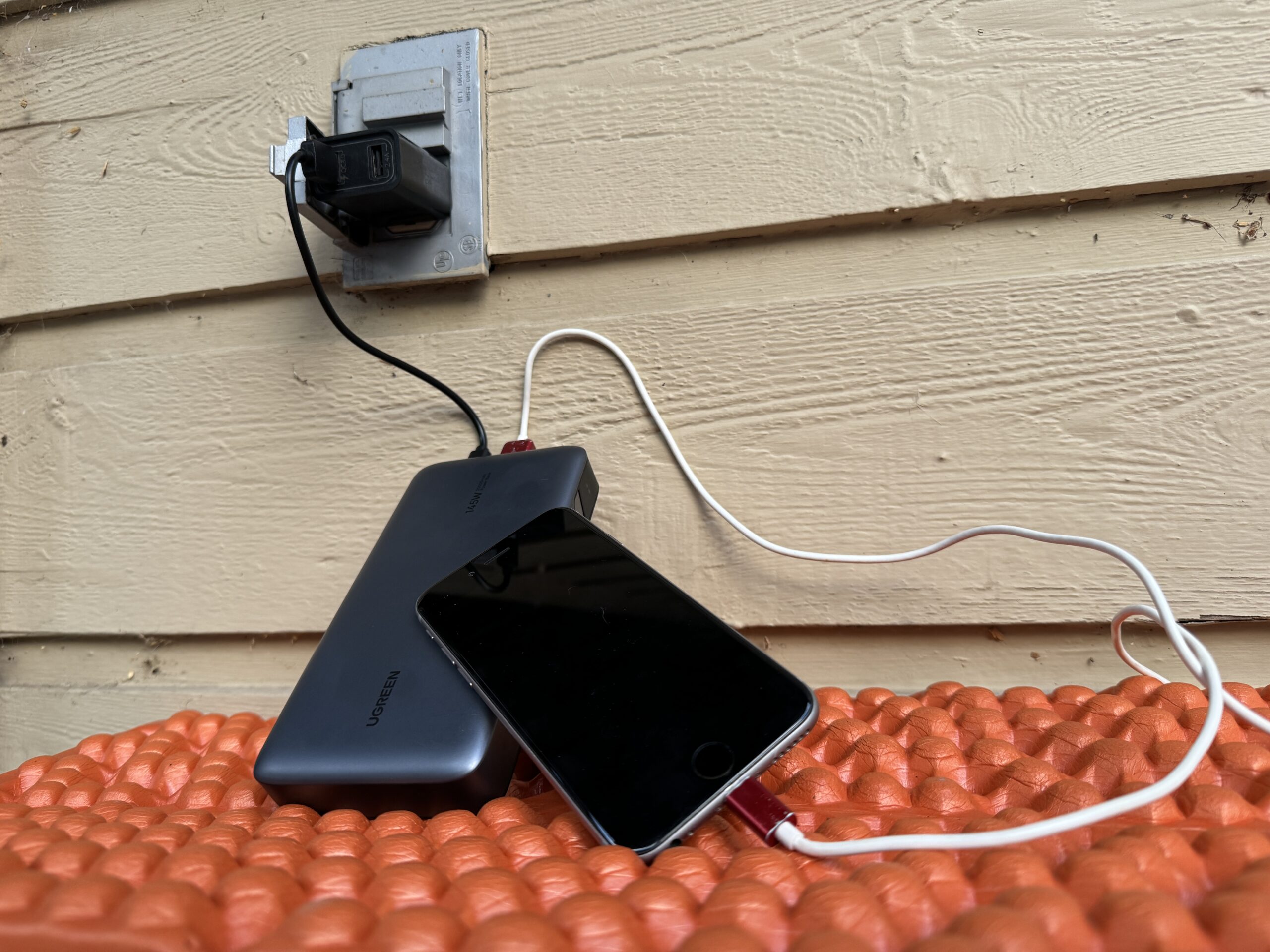 Close up of the UGREEN charging from an outlet and a cell phone charging from the power bank simultaneously.