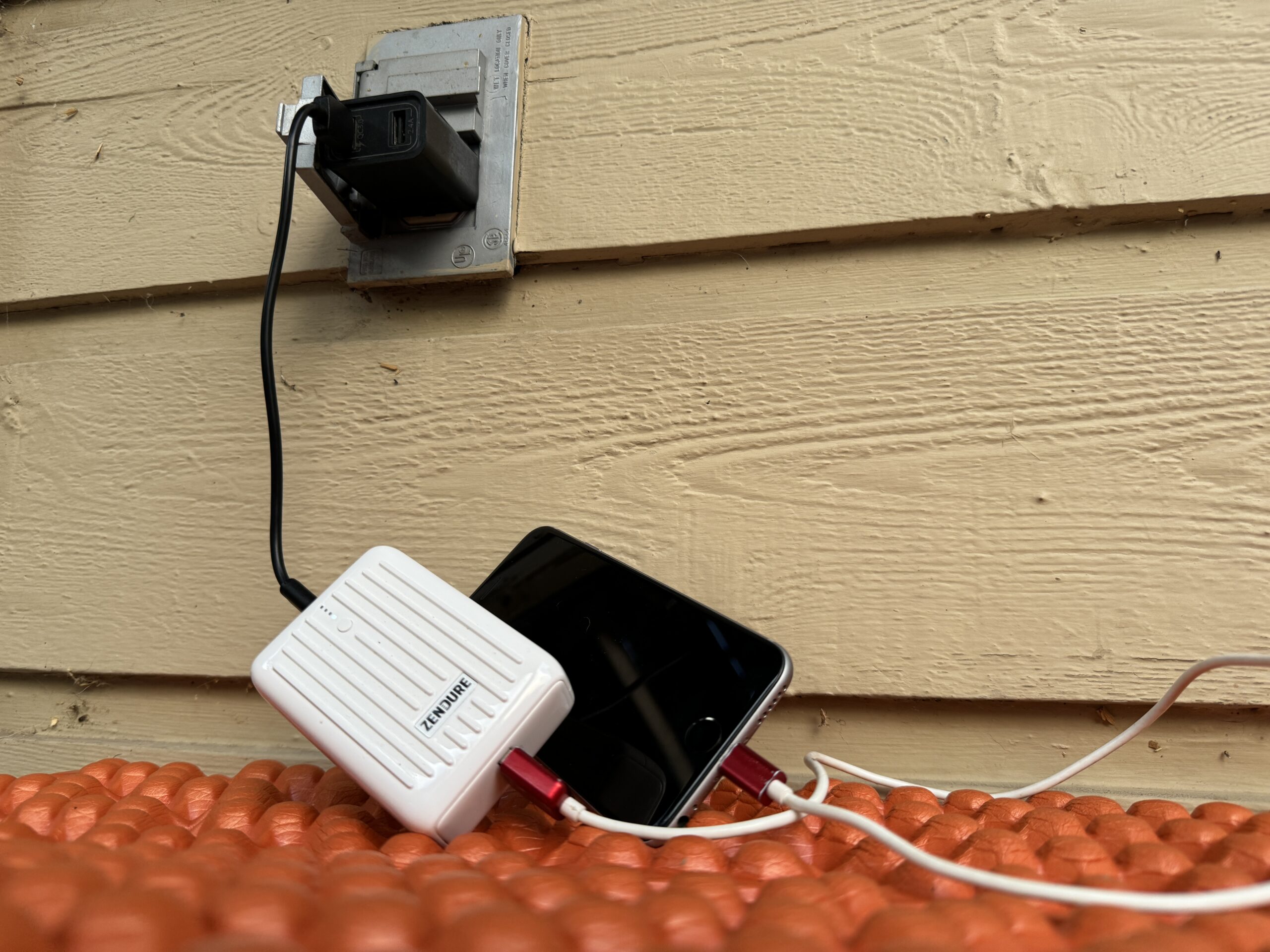 Close up of the Zendure charging from an outlet and a cell phone charging from the power bank simultaneously.