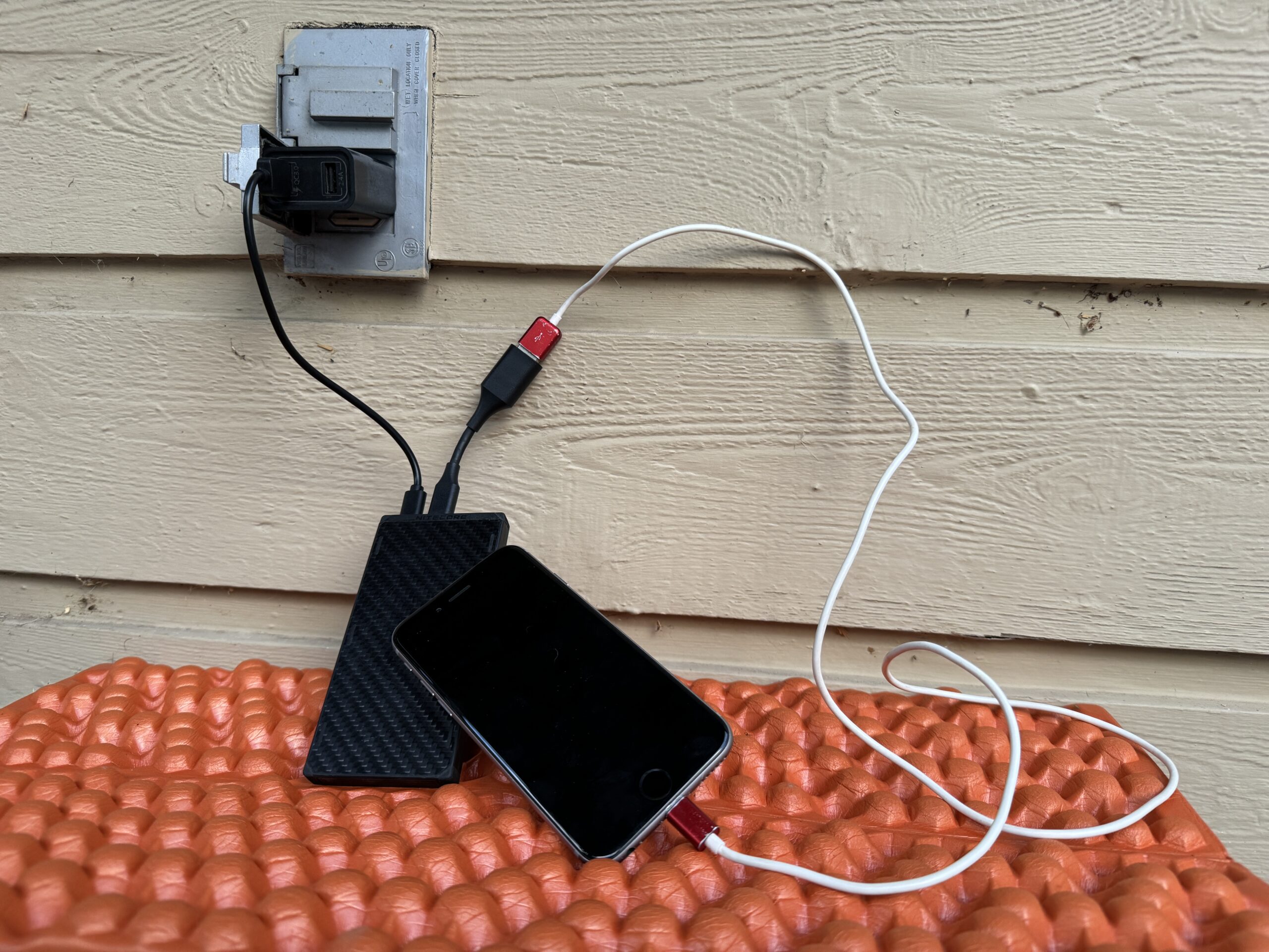 Close up of the Nitecore charging from an outlet and a cell phone charging from the power bank simultaneously.