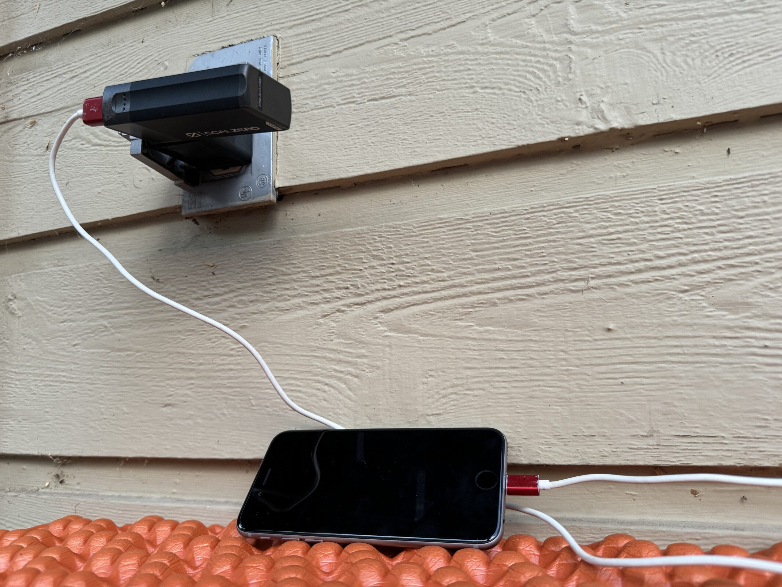 Close up of the Goal Zero charging from an outlet and a cell phone charging from the power bank simultaneously.