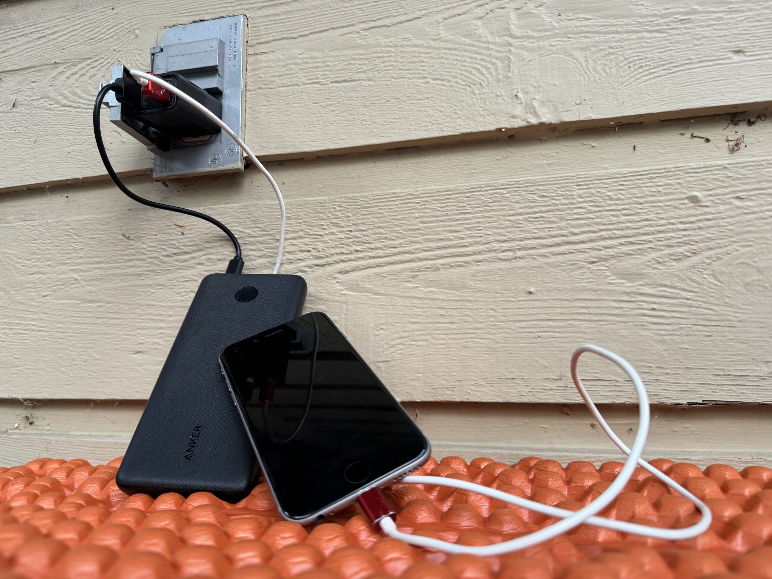 Picture of both the Anker power bank and a cell phone charging from the same wall plug.