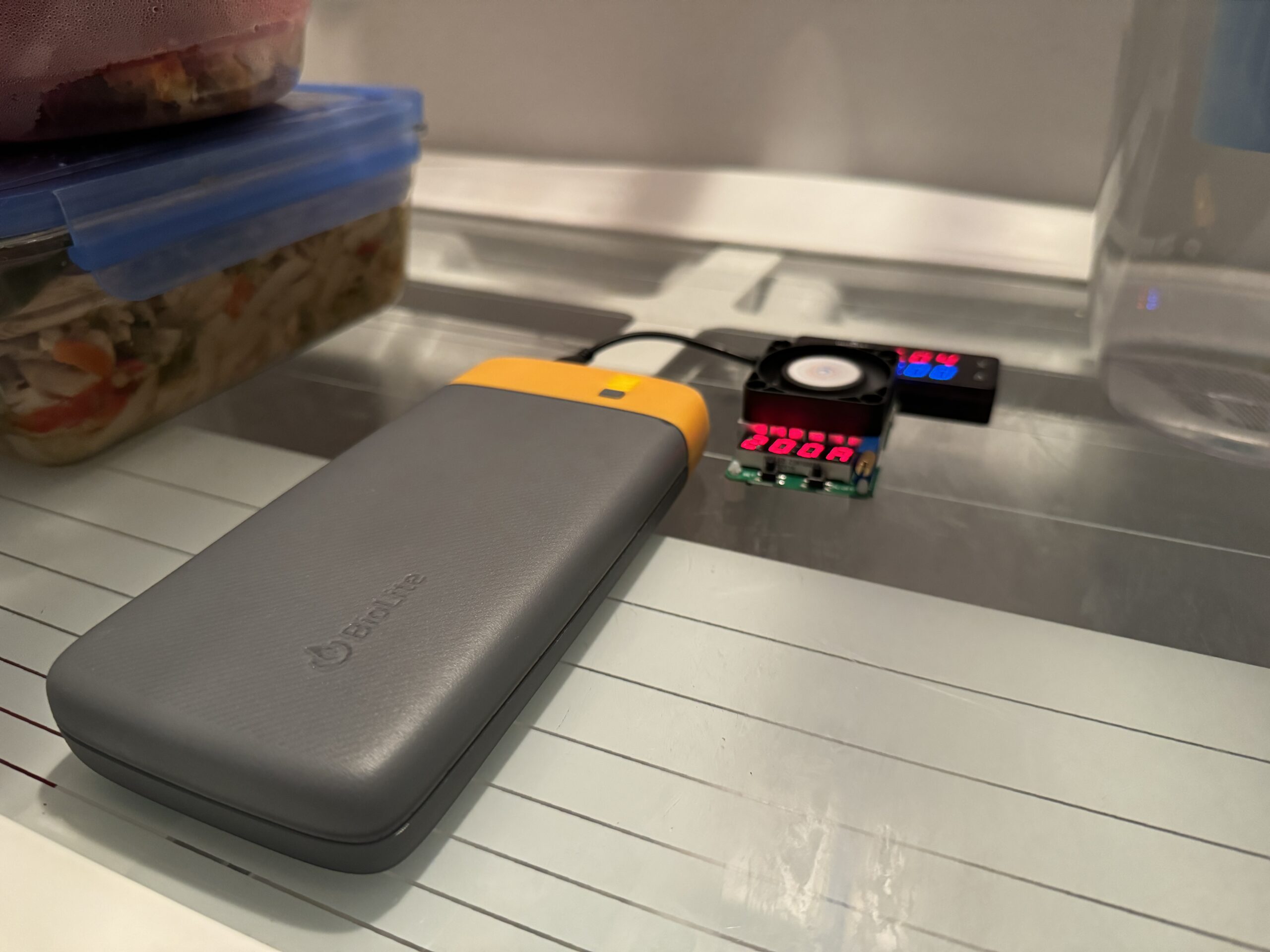 The BioLite power bank is hooked up to a multimeter and dummy resistor load inside a refrigerator with food.