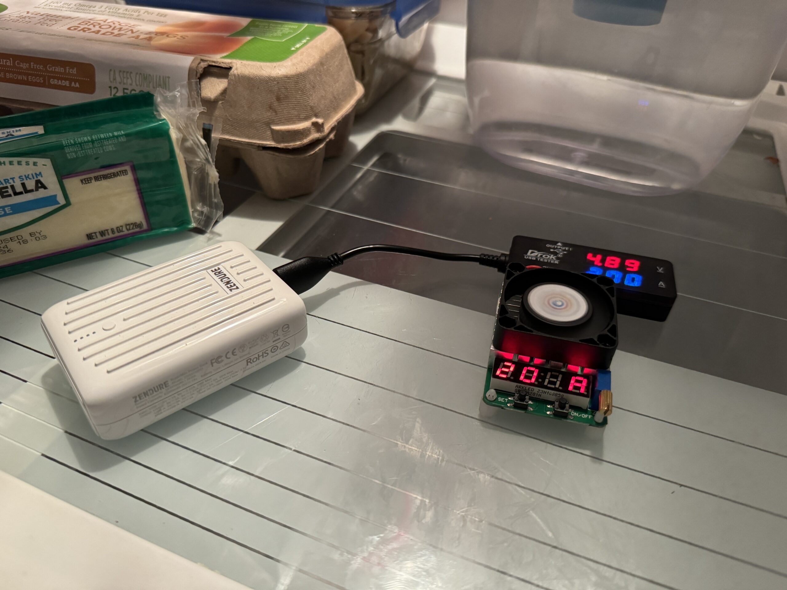 The Zendure power bank is hooked up to a multimeter and dummy resistor load inside a refrigerator with food.