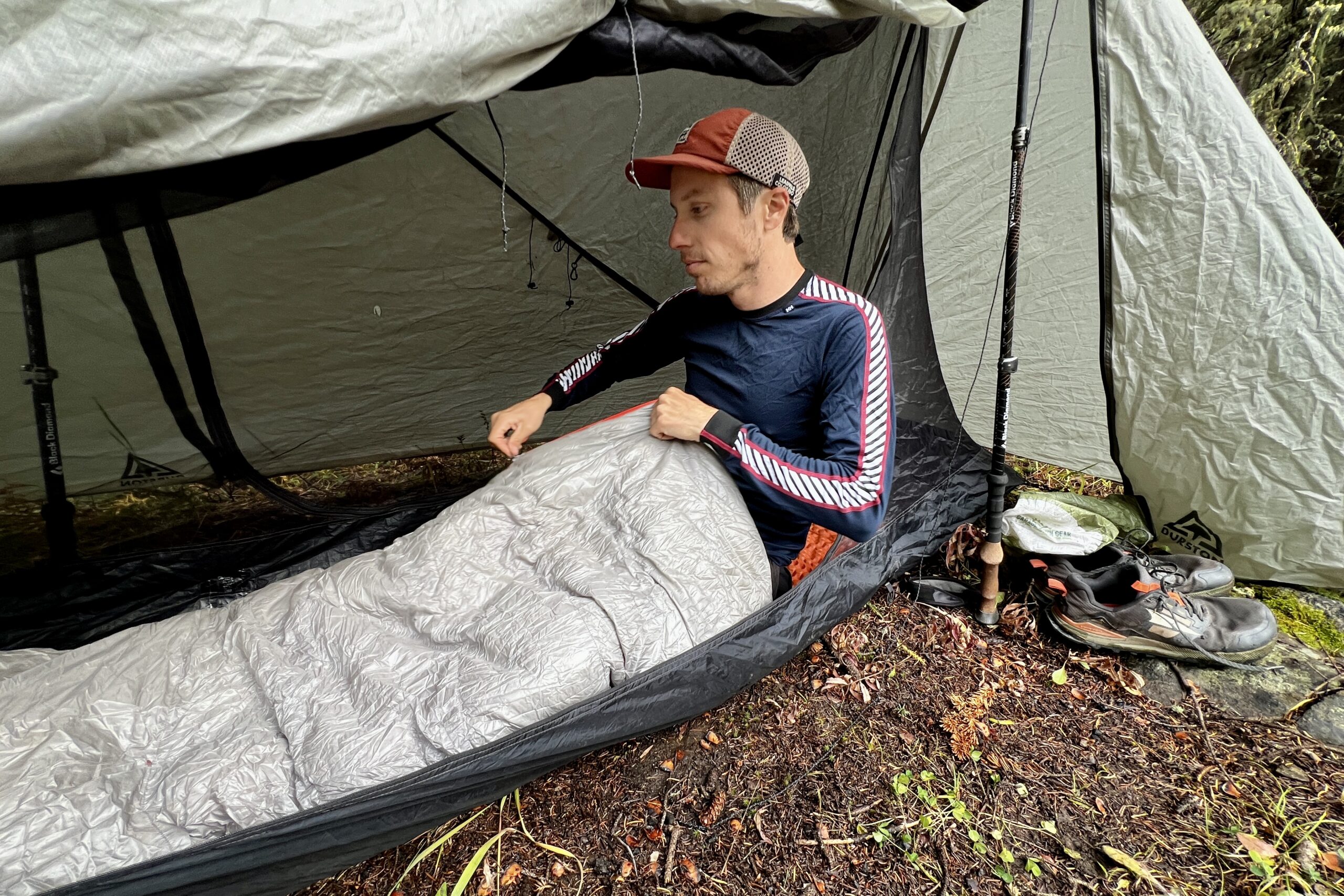 A hiker sitting in his sleeping bag in a tent while wearing the Helly Hansen Lifa Stripe base layer.