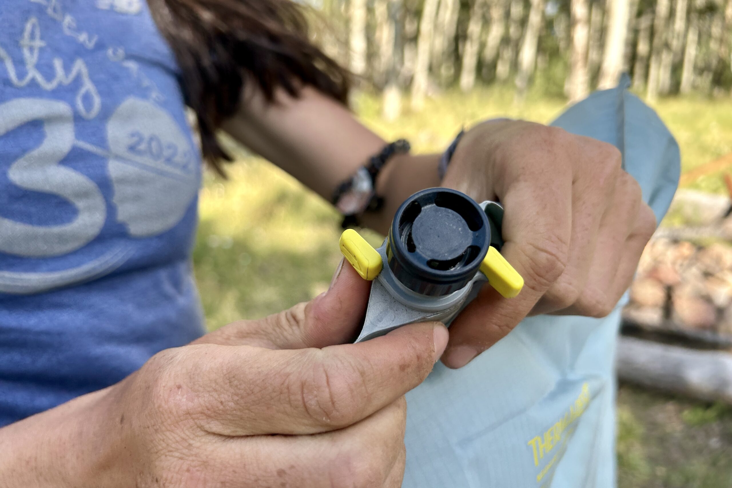 Close up of a person's hands opening a single valve on the Sea to Therm-a-Rest NeoAir XTherm NXT.