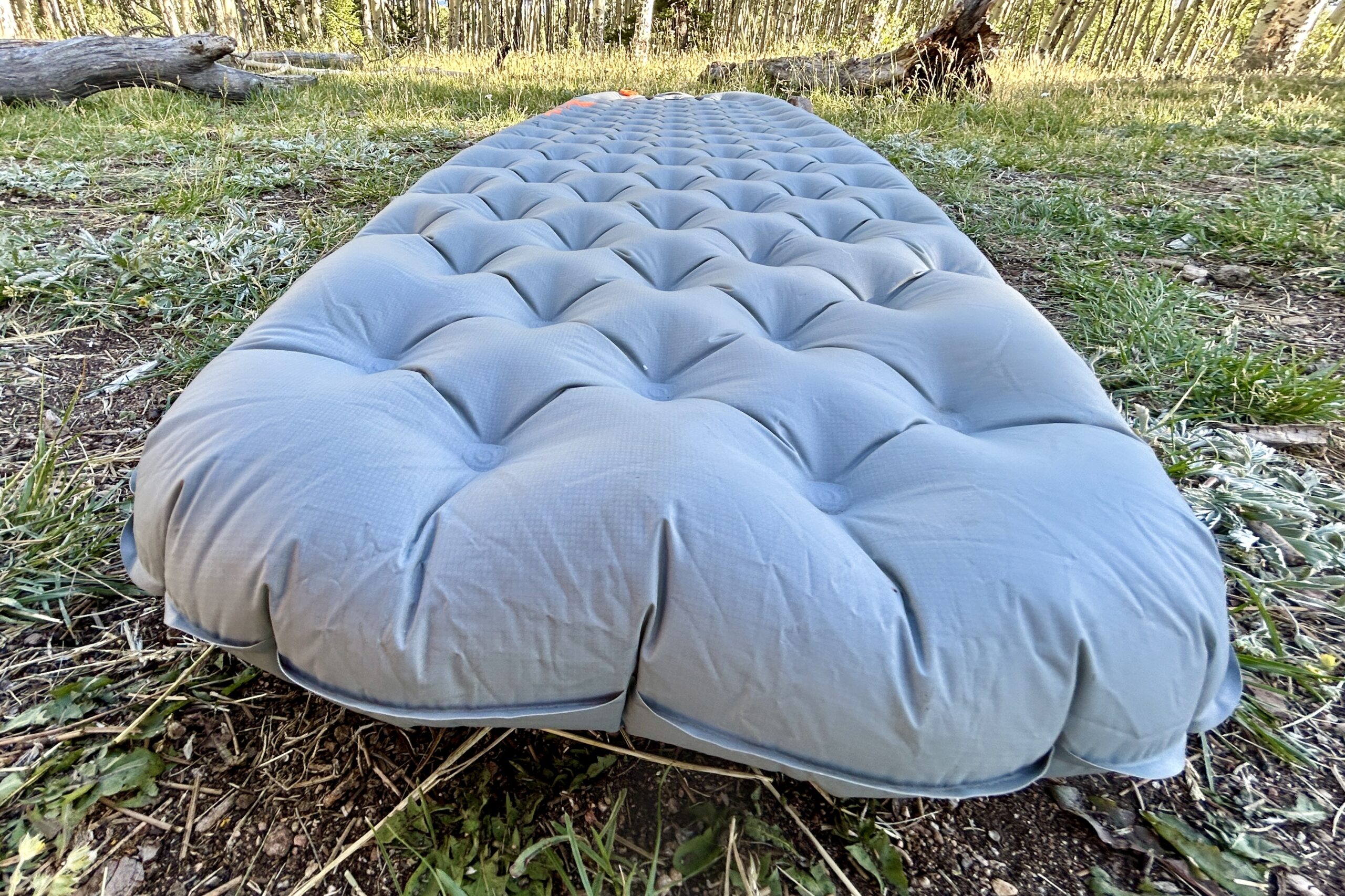 A grey sleeping pad rests on the ground.