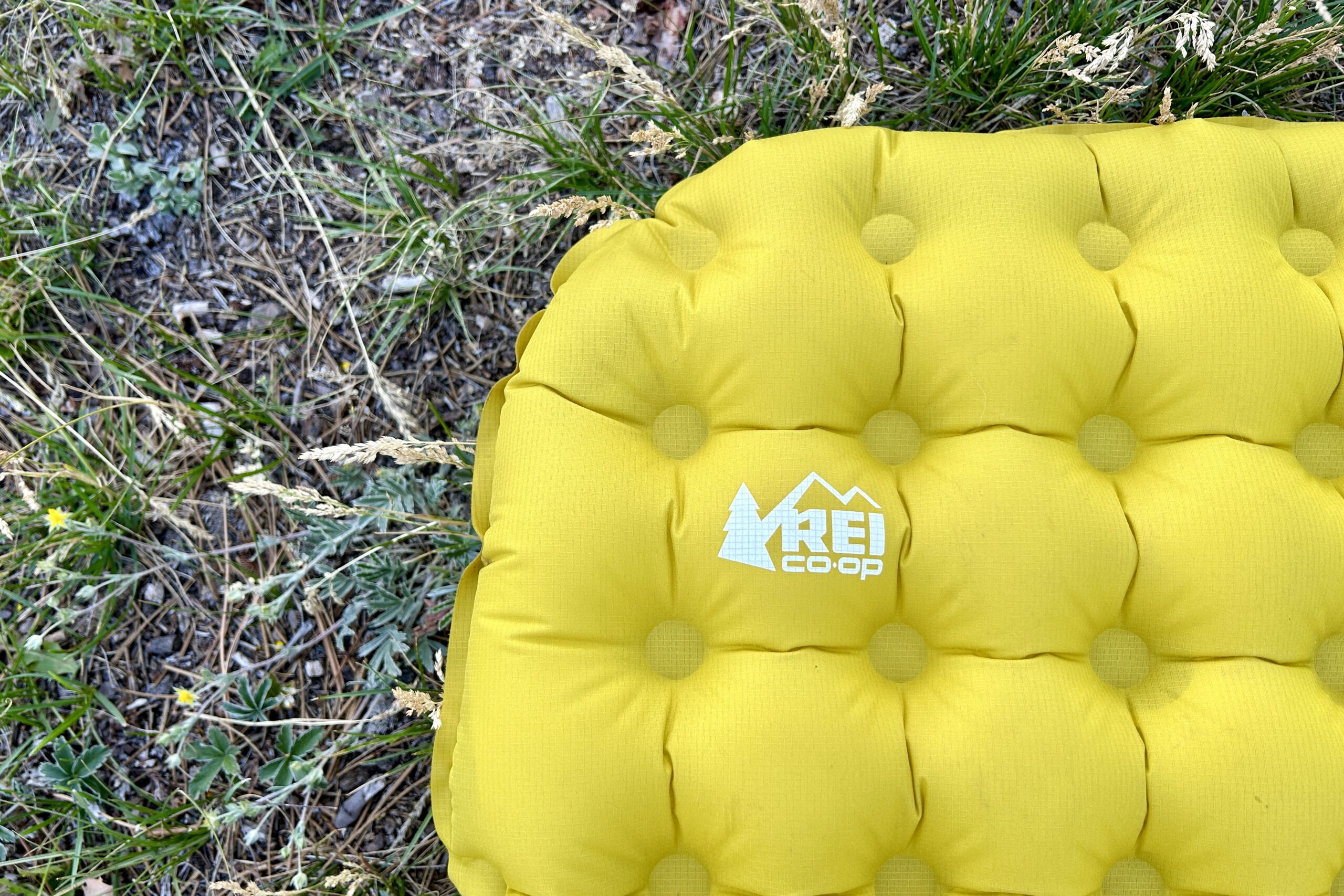 Close up of a yellow inflatable camping pad with it's quilted pattern clearly visible and the REI logo right of center.