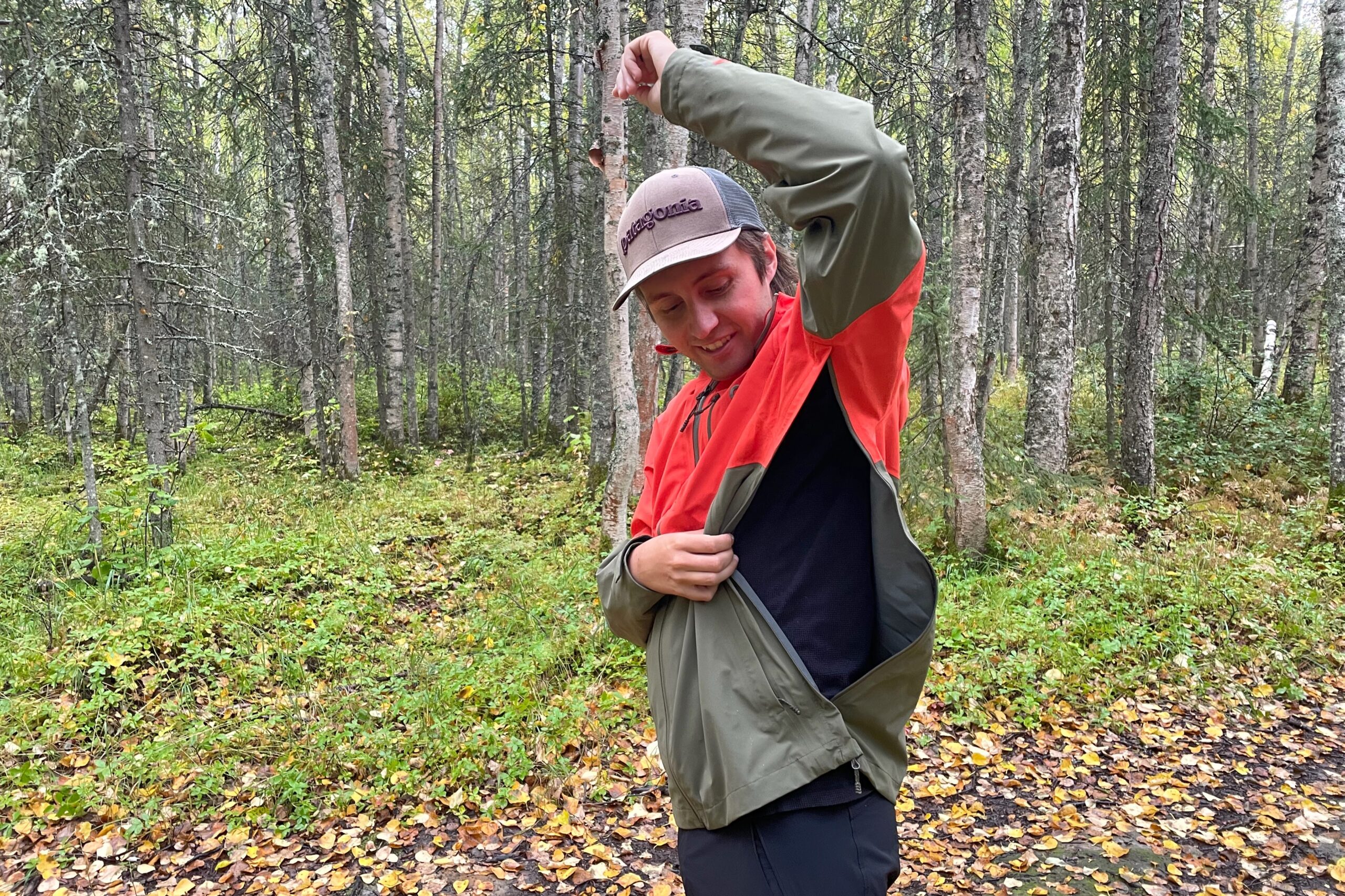 A man unzips the vents of his rain jacket.