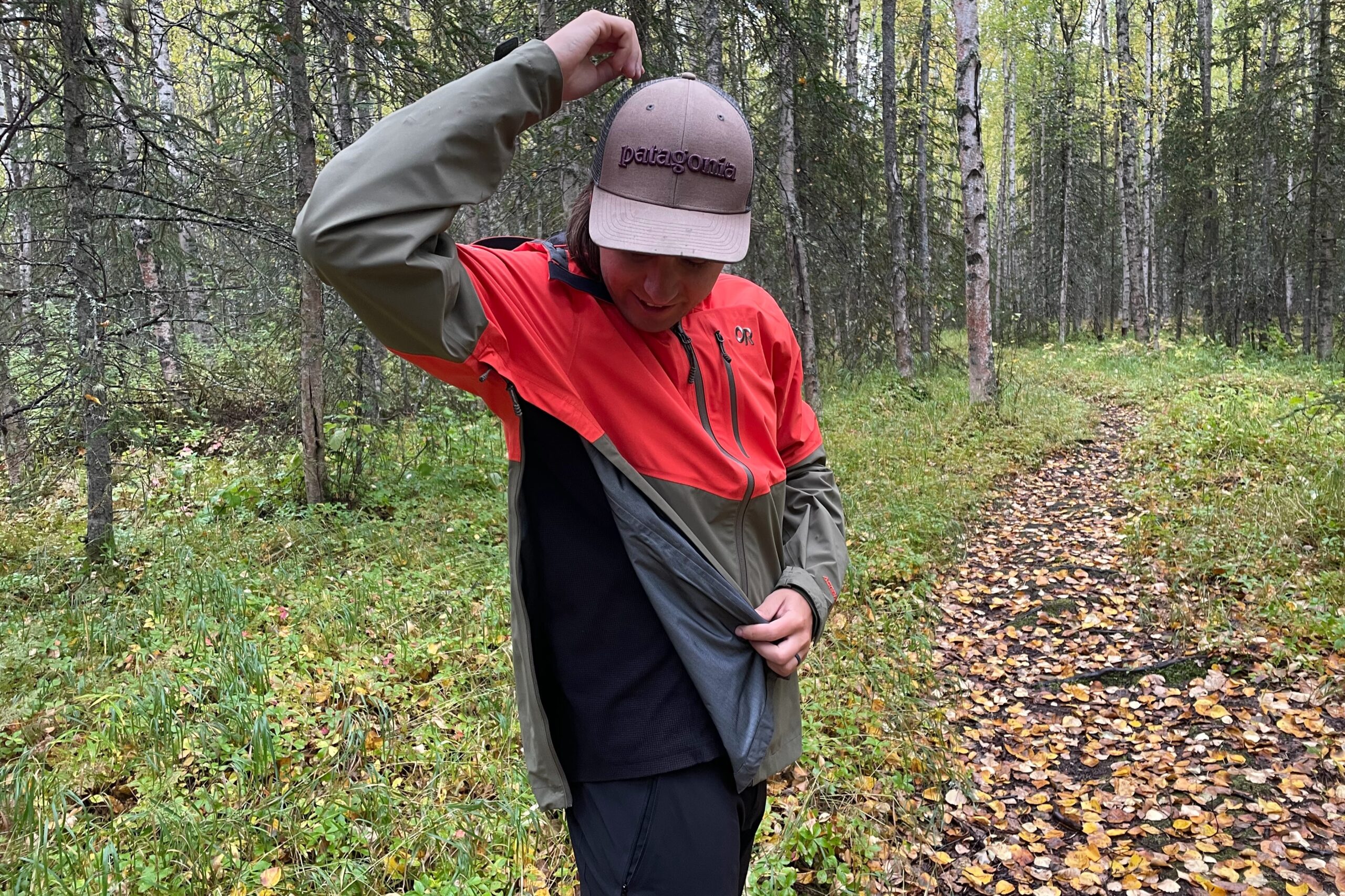 A man unzips his rain jacket for ventilation.