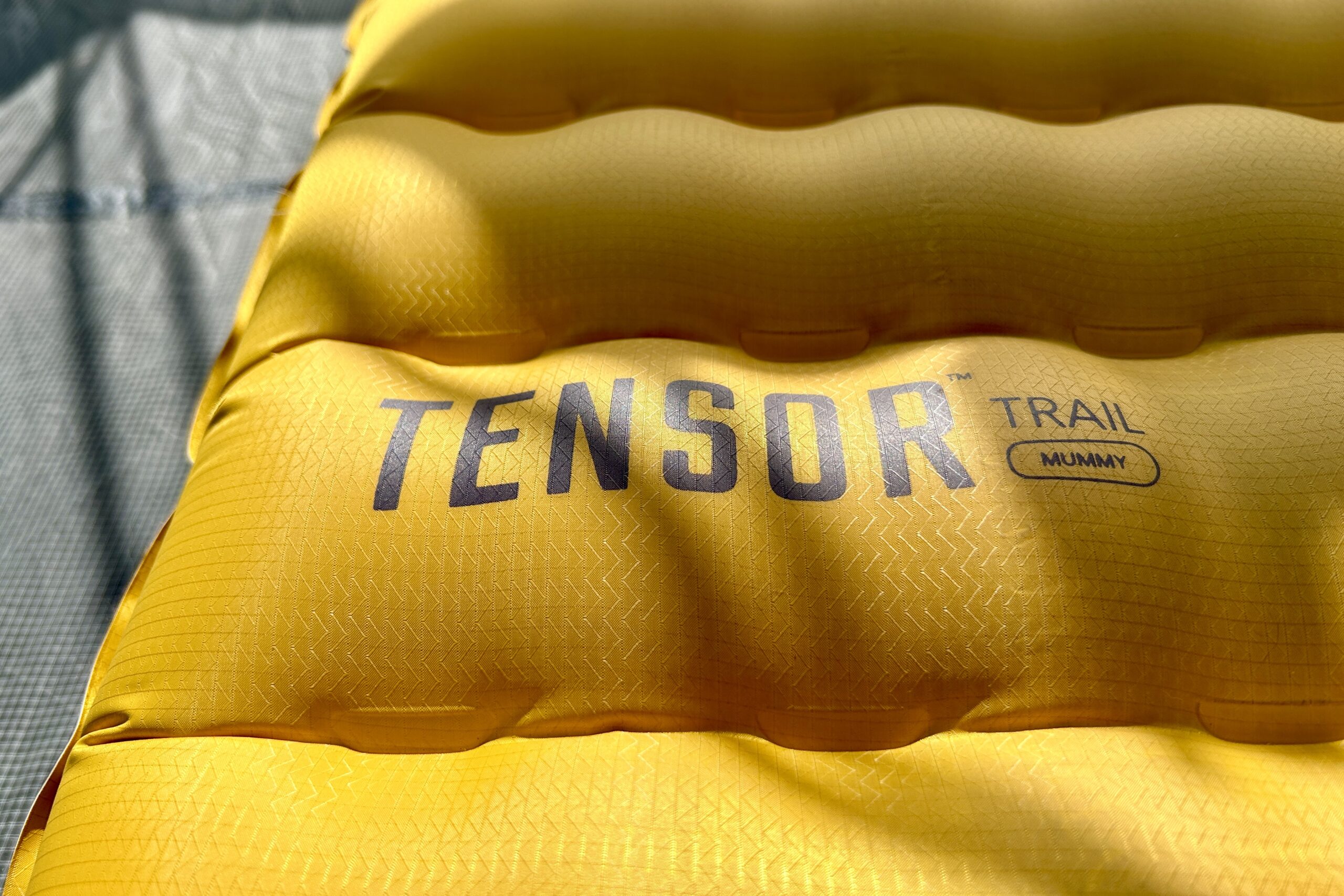 Close up of a Tensor Trail sleeping pad laid out on the ground with its baffles inflated.