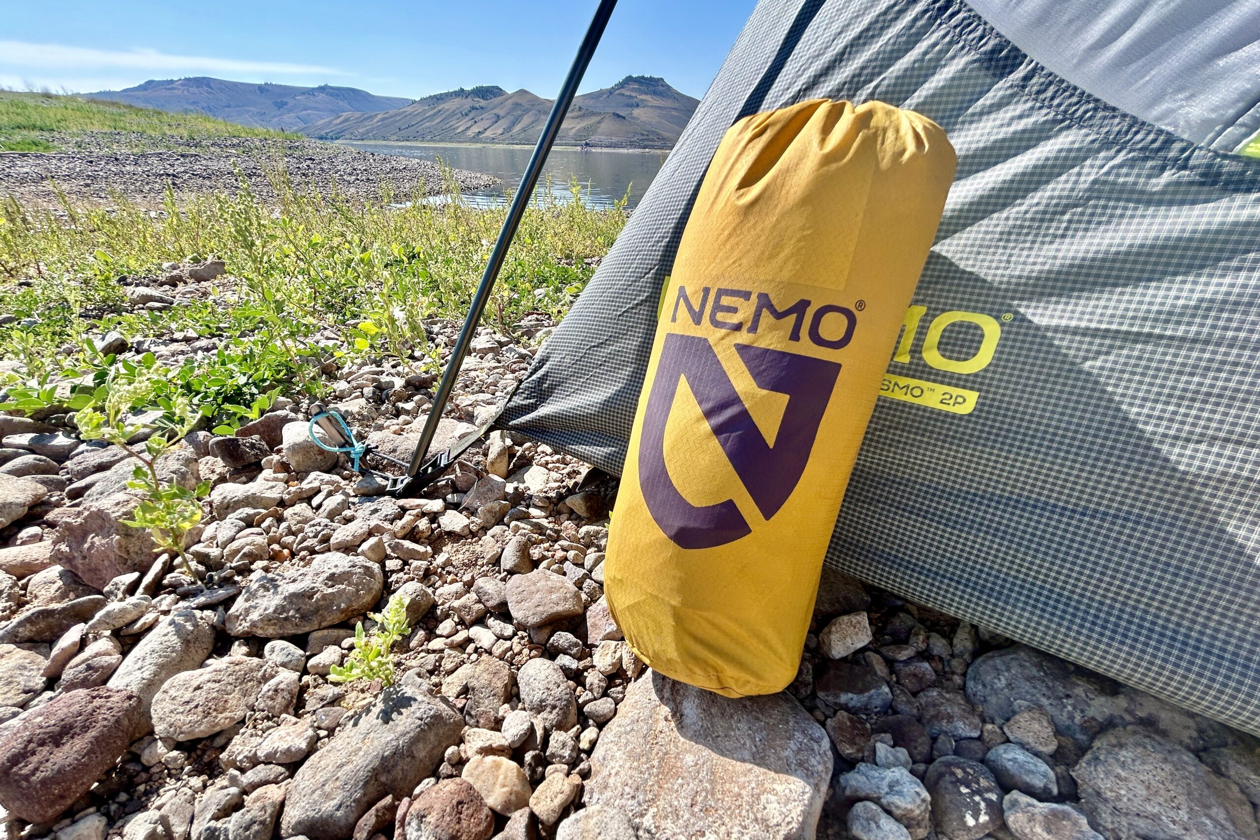 Close up image of the ackaged Tensor Trail sleeping pad in its stuff sack leaning against a tent.