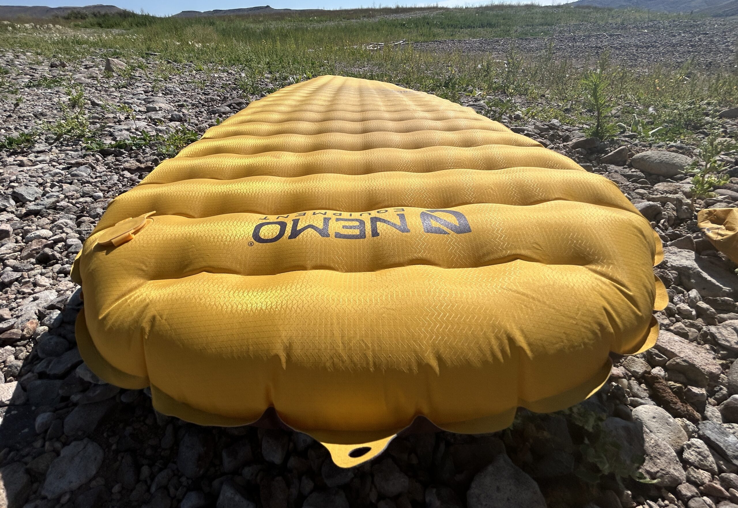 A yellow sleeping pad is spread out on the ground.