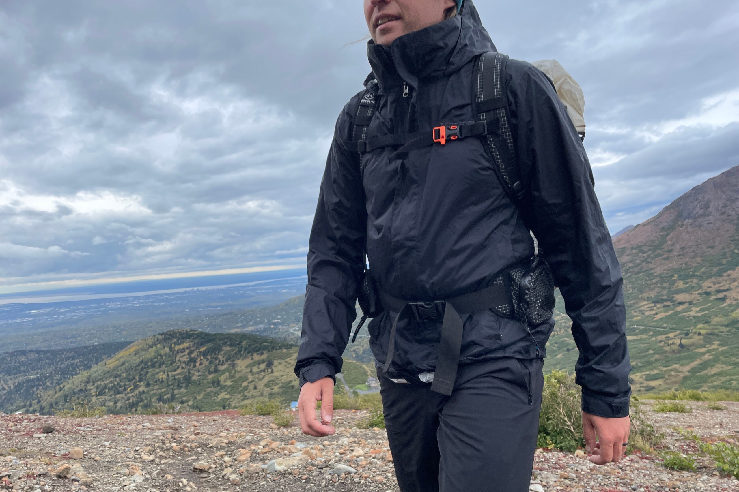 A closeup of the front of a rain jacket worn by a man hiking uphill