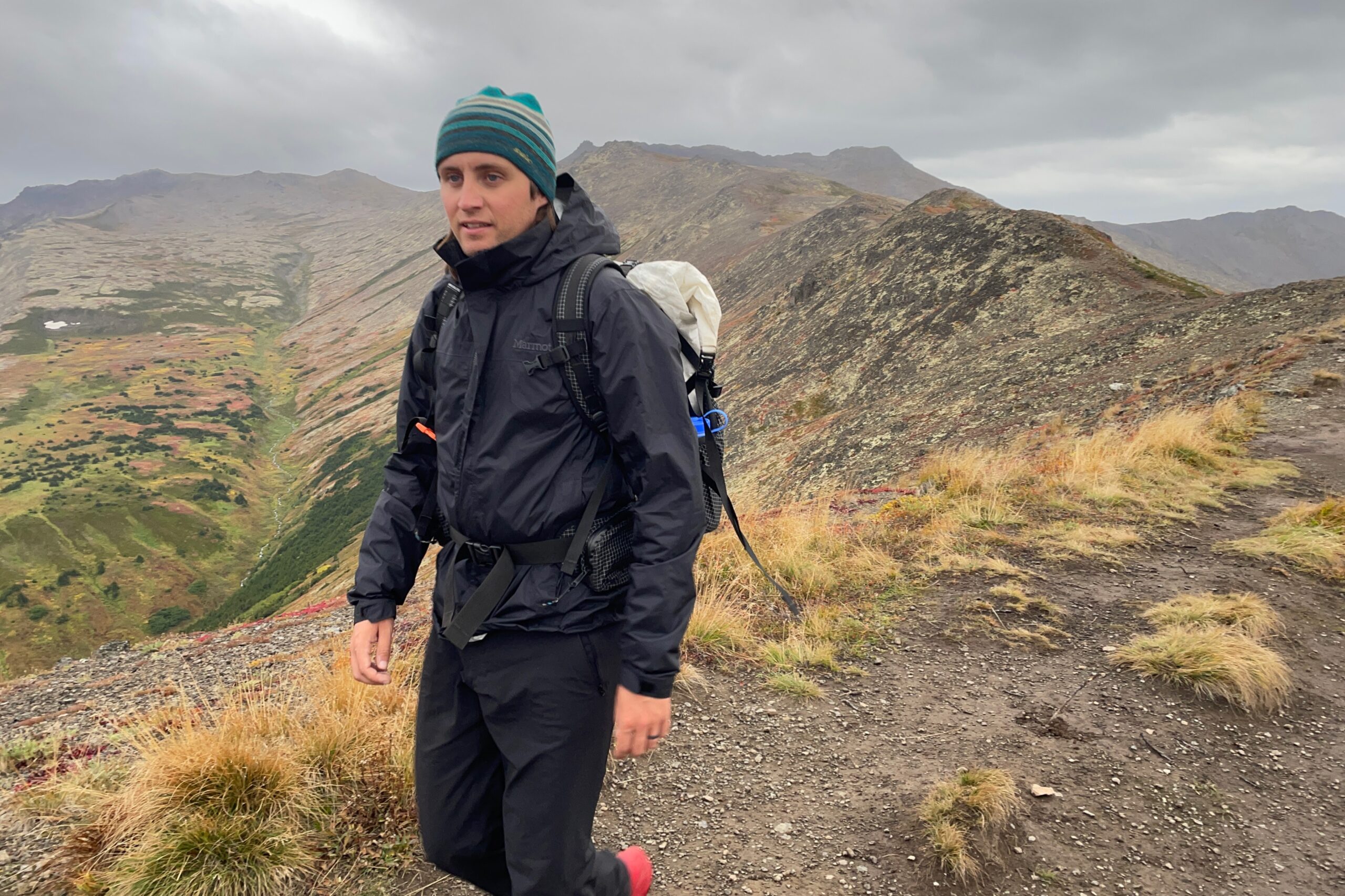 A man hikes along an alpine ridge in the rain