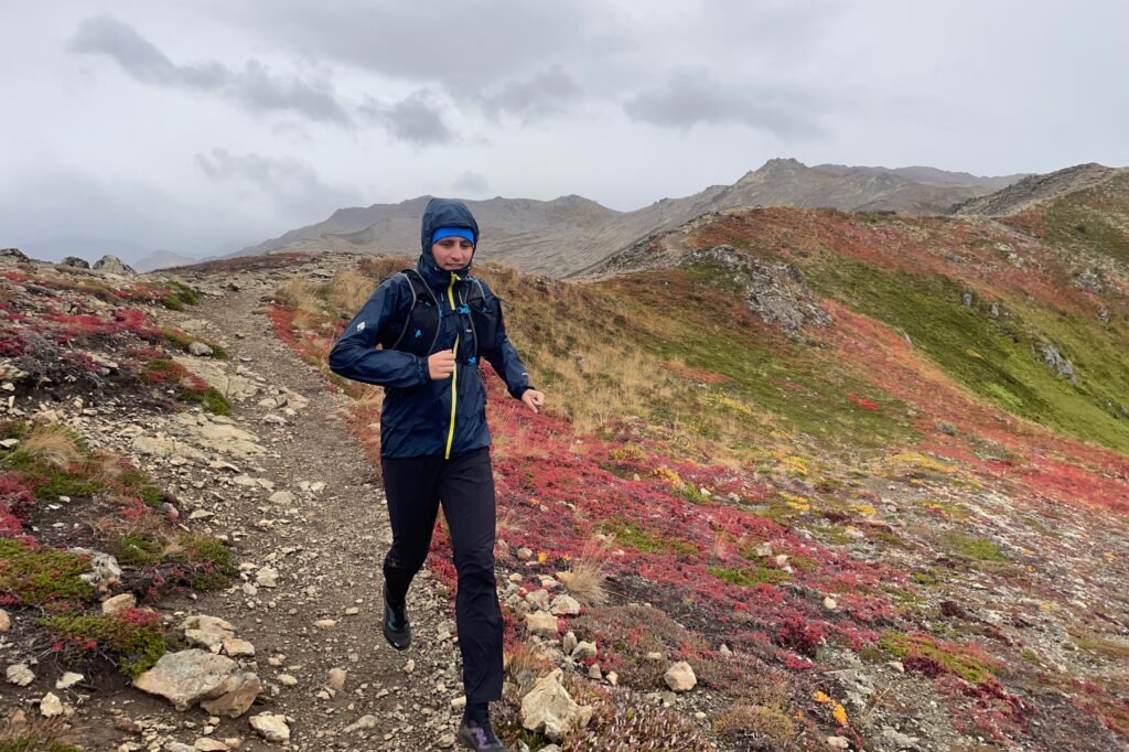 A man wearing a running vest runs through fall colors