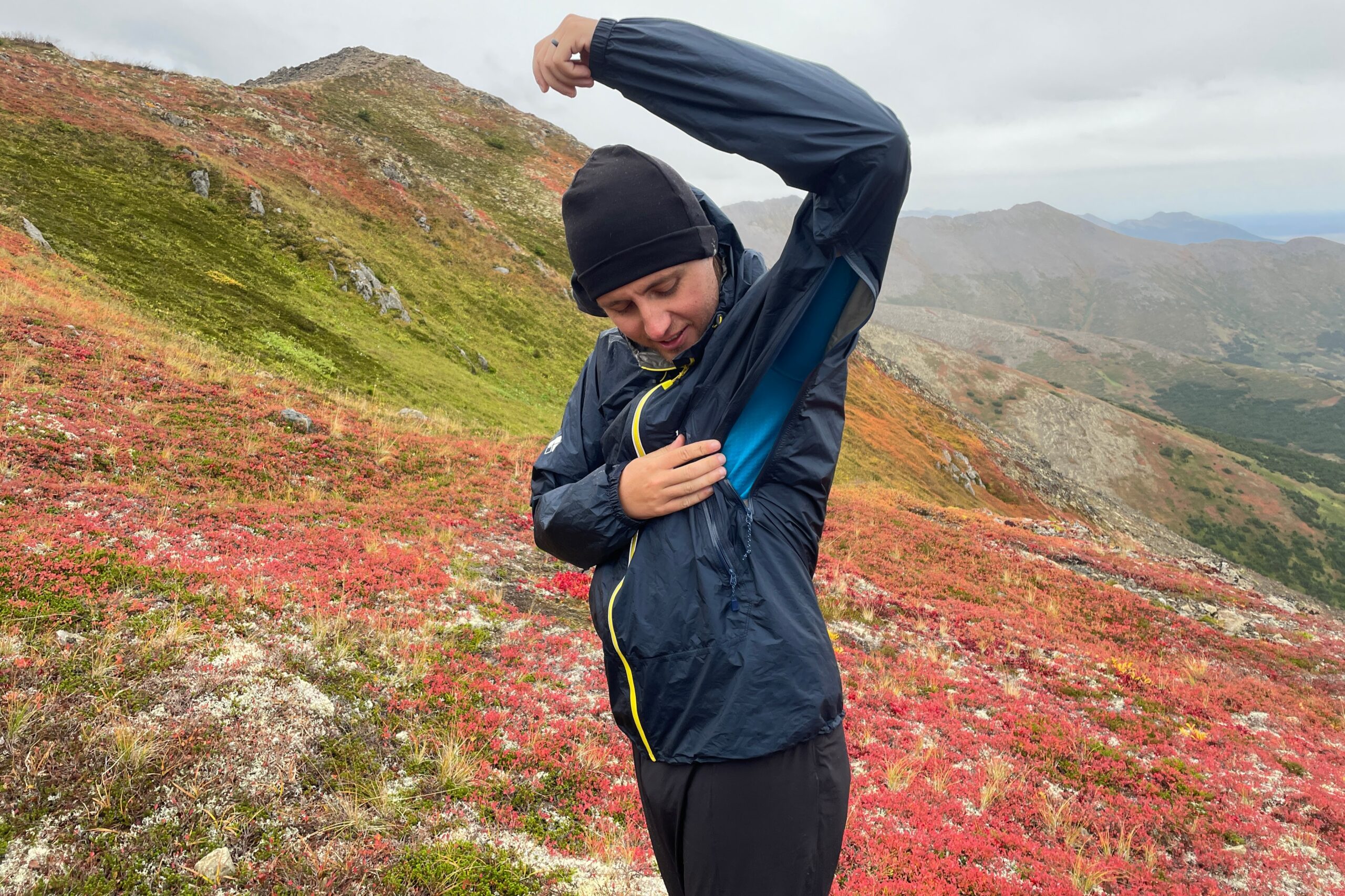 A man unzips vents under the arms of his rain jacket.