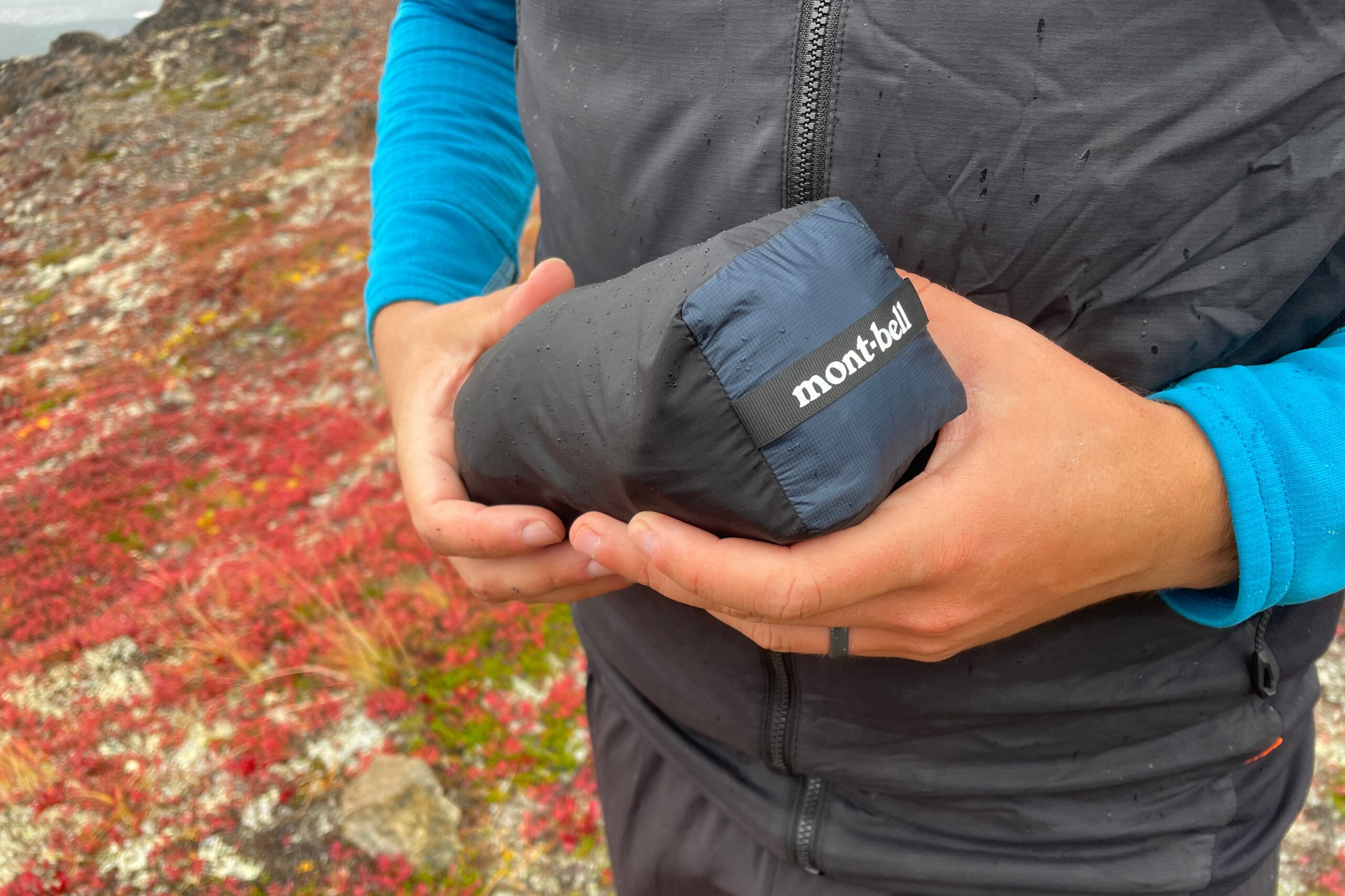 A man holds a rain jacket packed into a bundle.