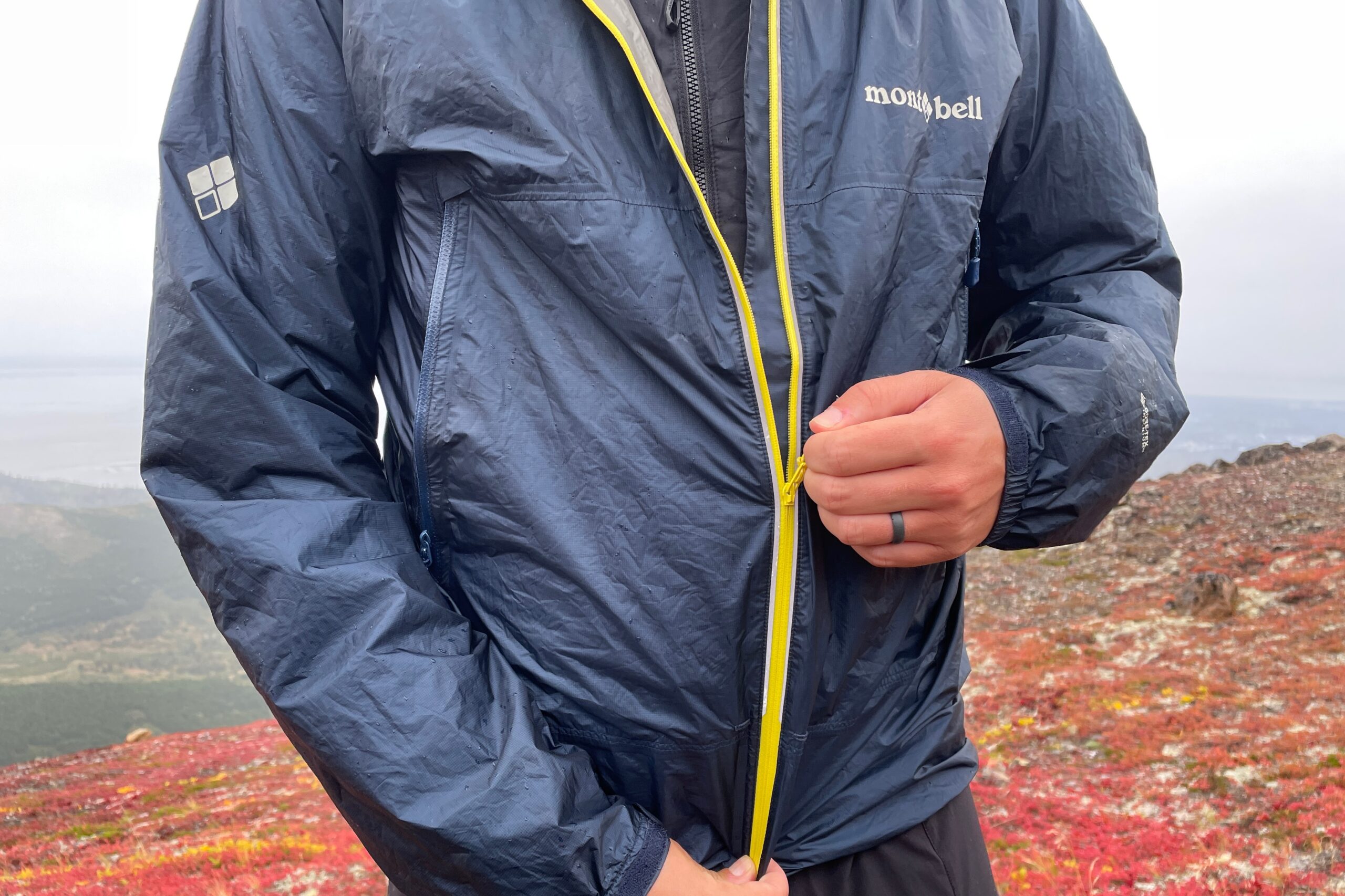 A man zips up his rain jacket in colorful alpine tundra.