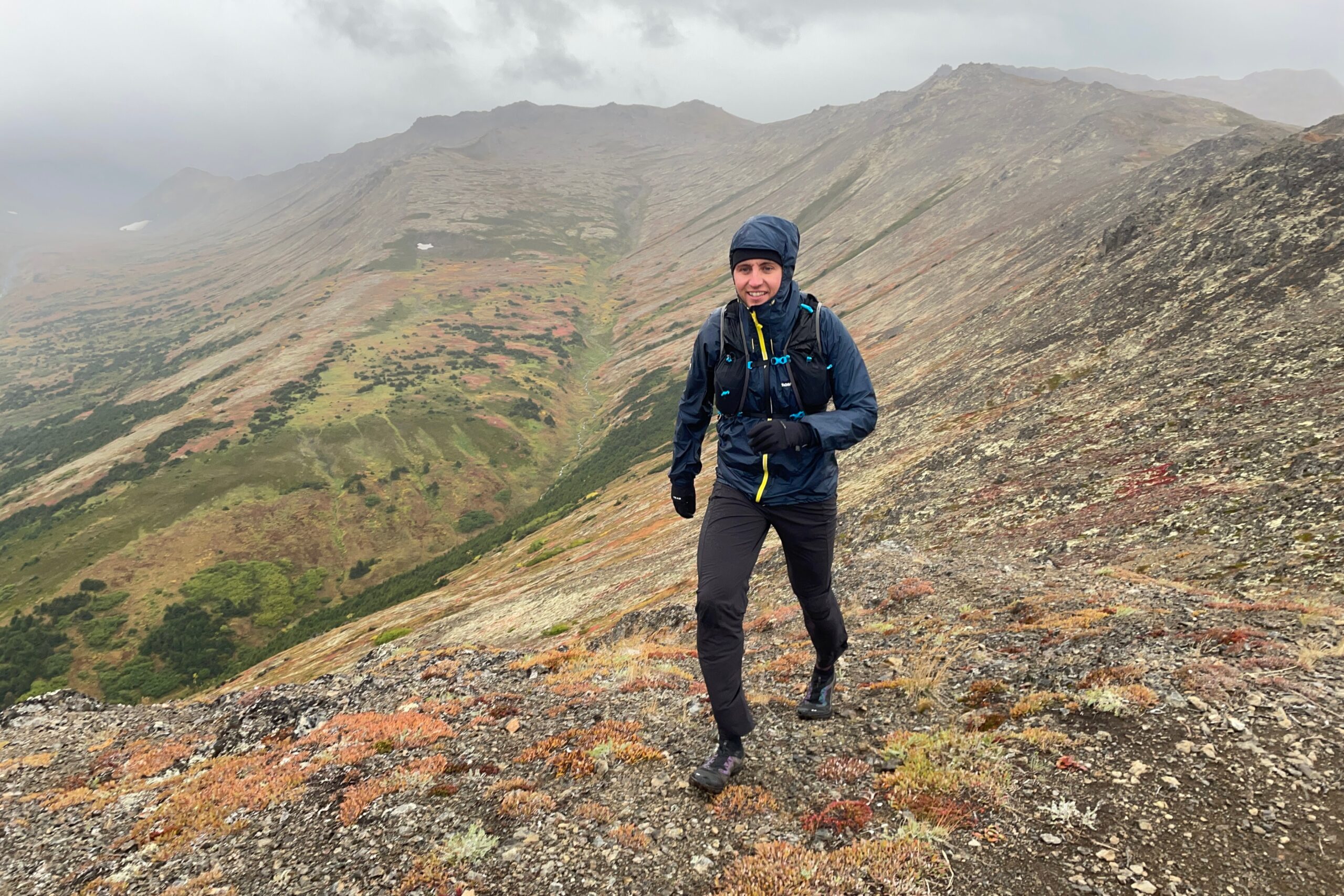 A man hikes along a ridge in rainy weather.